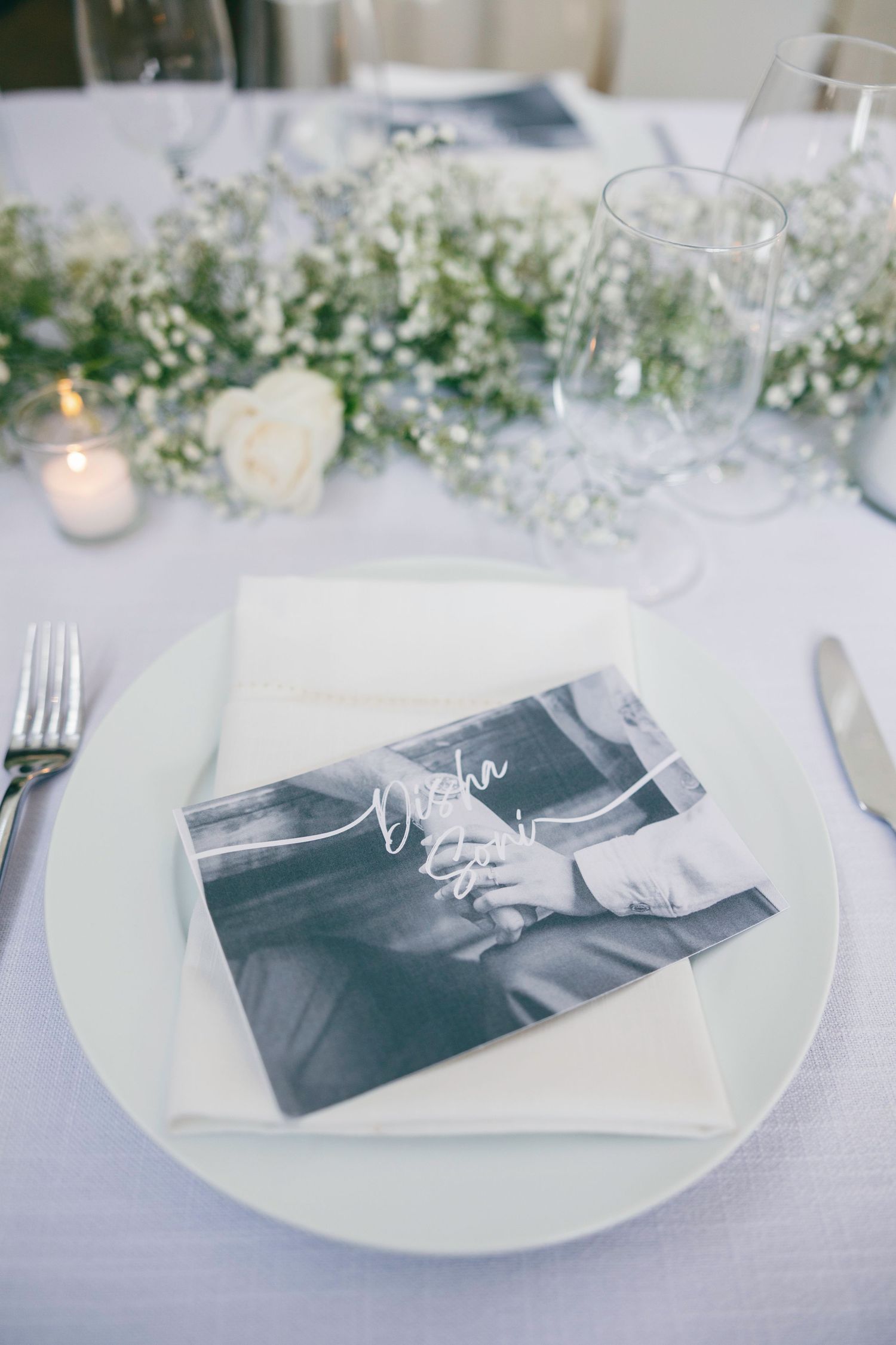 Wedding place settings feature black and white photos with delicate baby's breath flowers.