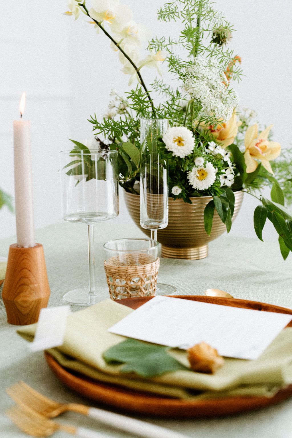 Minimalist table setting with white flowers, candles and wooden accents.