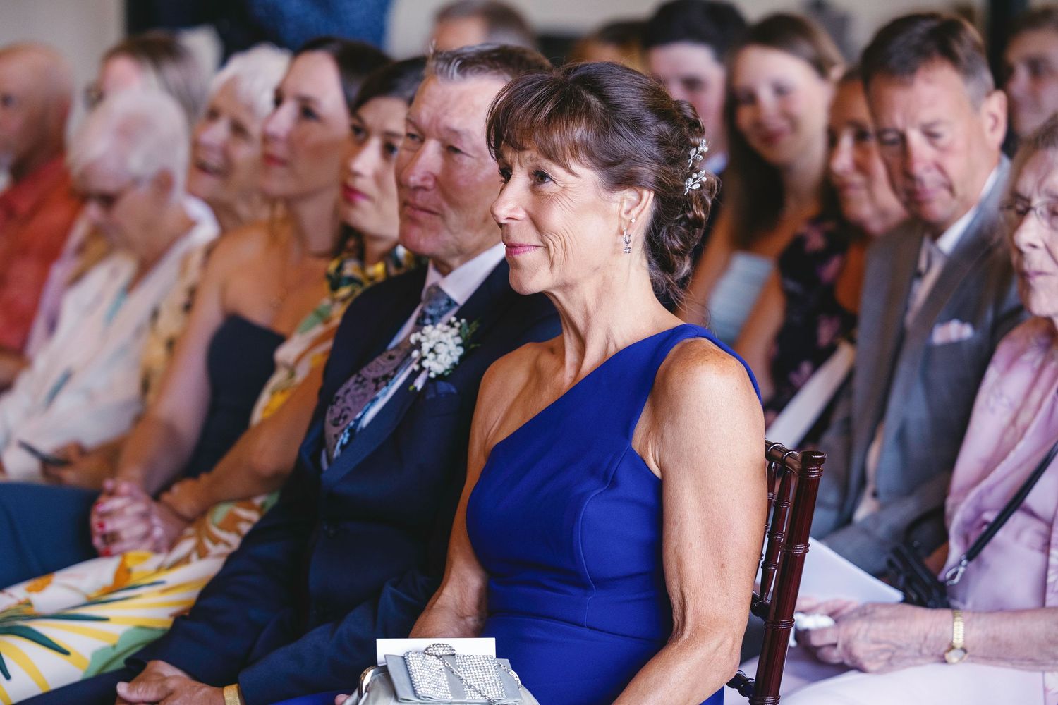Wedding guests seated in rows watch attentively during the ceremony.