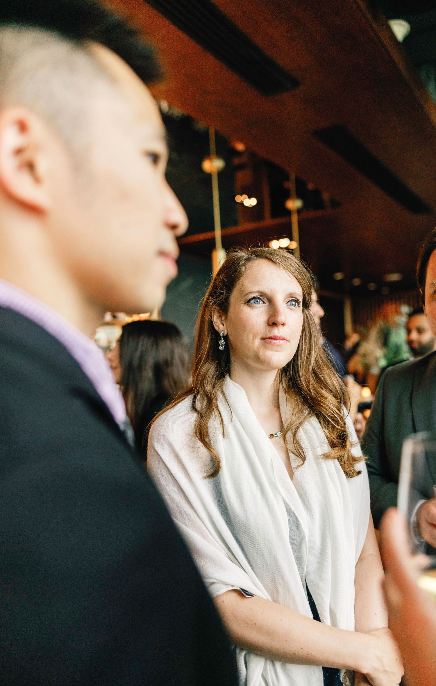 Guests mingling at an elegant indoor event with soft lighting and formal attire.