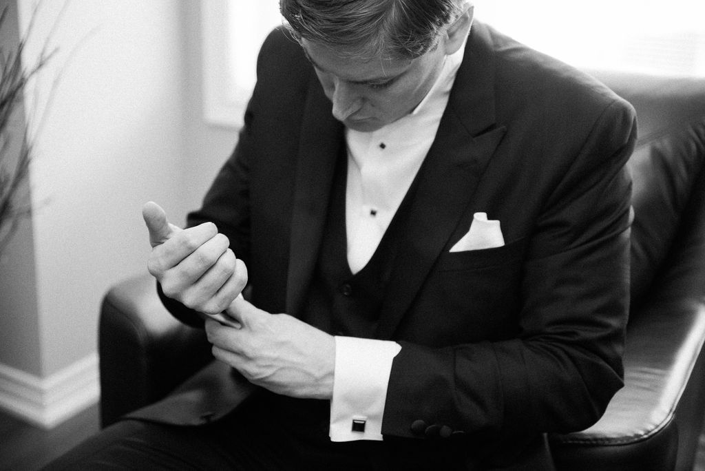 A couple in formal wedding attire shares an intimate moment together in a black and white photograph.