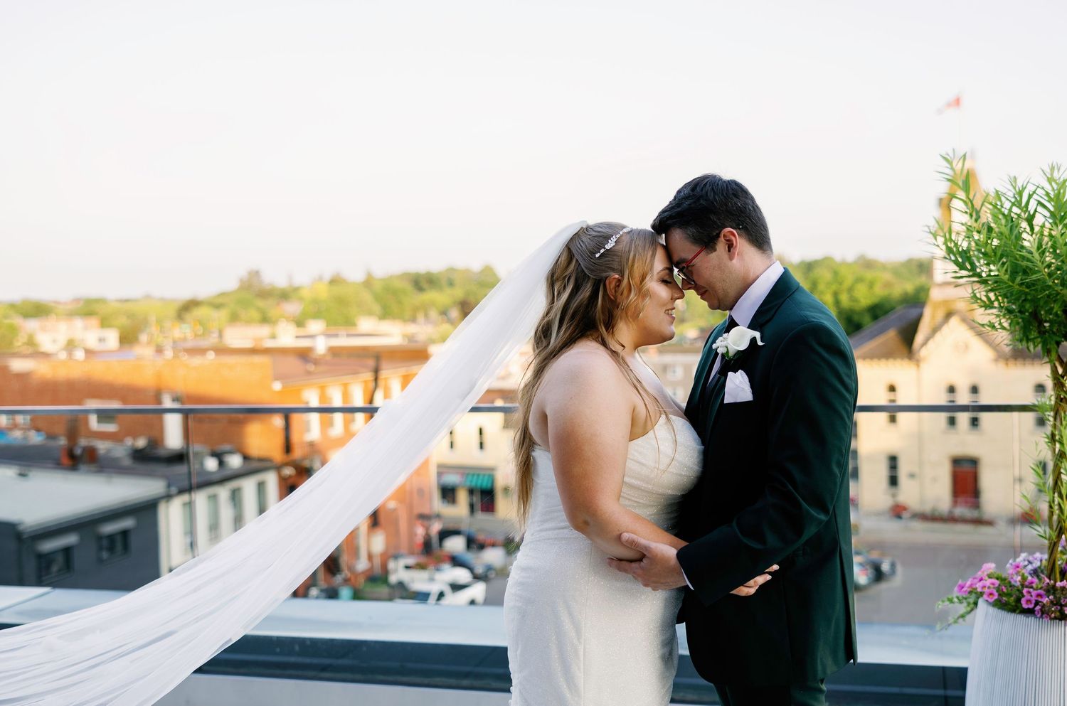 Wedding couple poses against urban rooftop setting during golden hour.