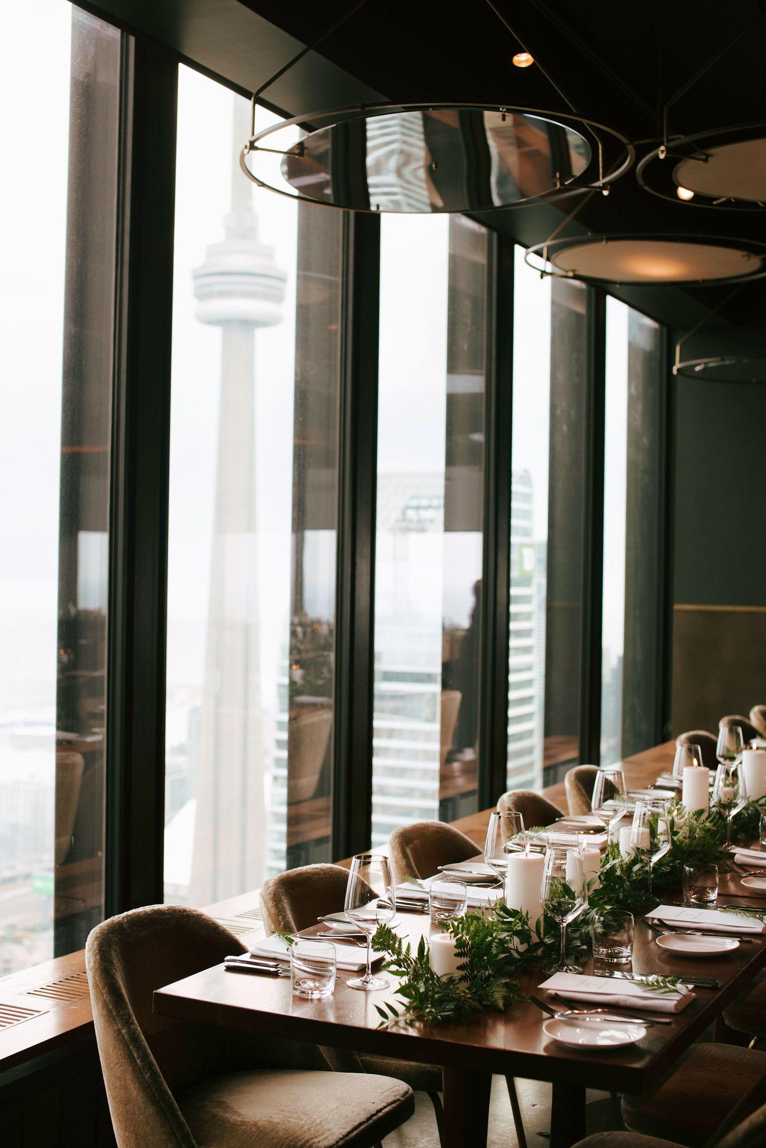 Modern restaurant interior with floor-to-ceiling windows, plush seating, and sophisticated table settings.