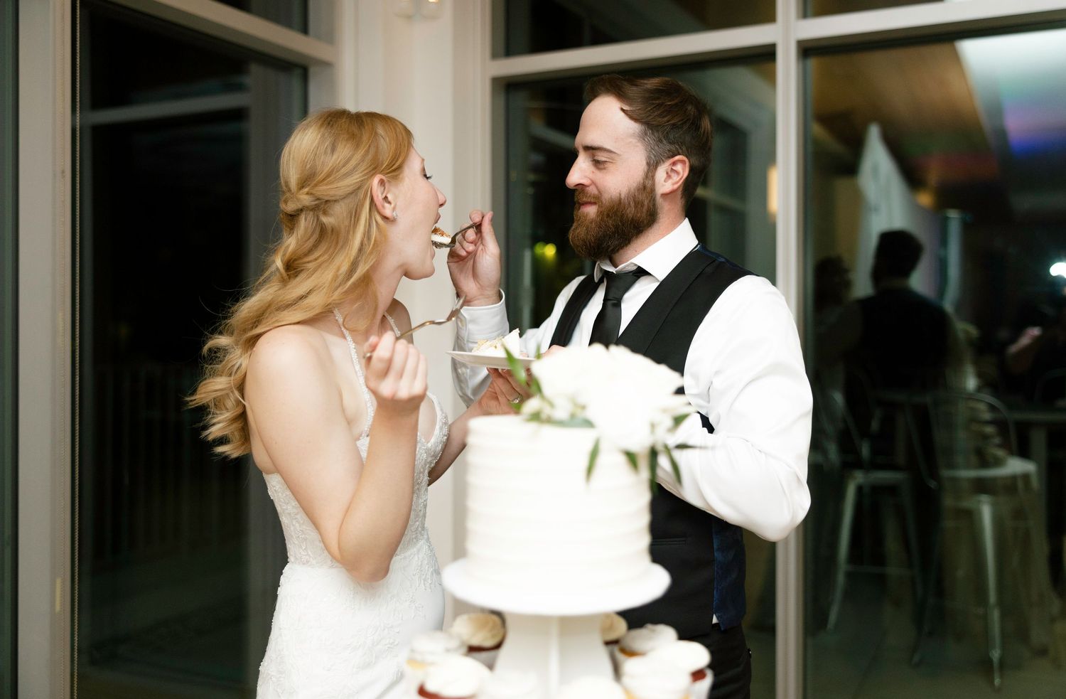 A bride and groom share a playful moment while cutting their wedding cake during their reception celebration.