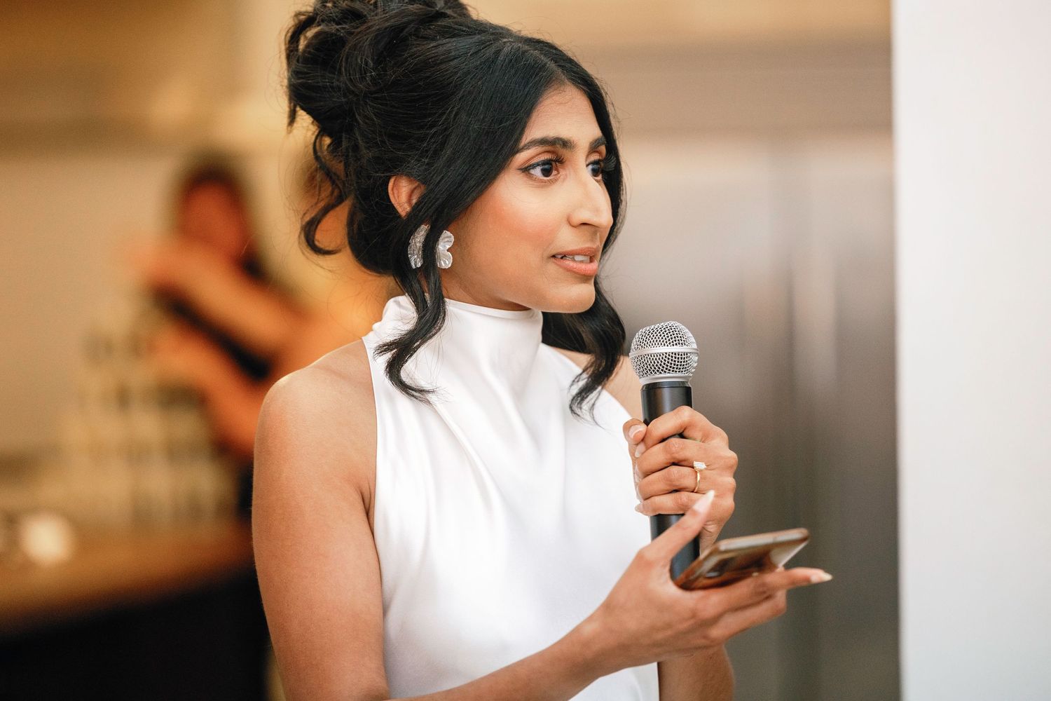 Bride speaking into microphone during wedding reception speech.