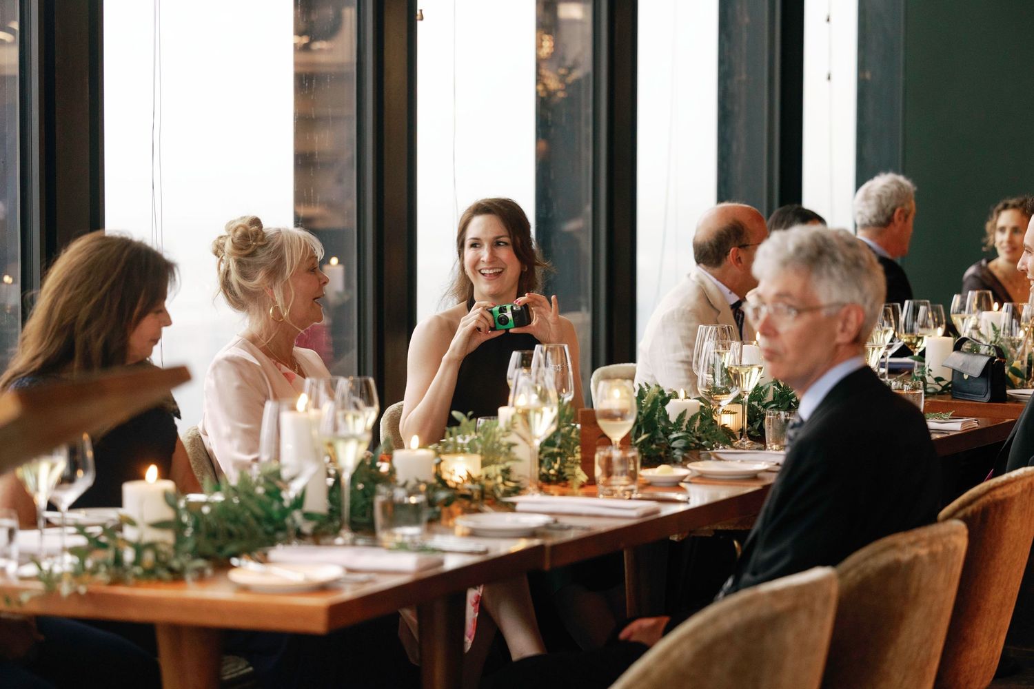 Diners enjoying a social gathering at an upscale restaurant with window views.
