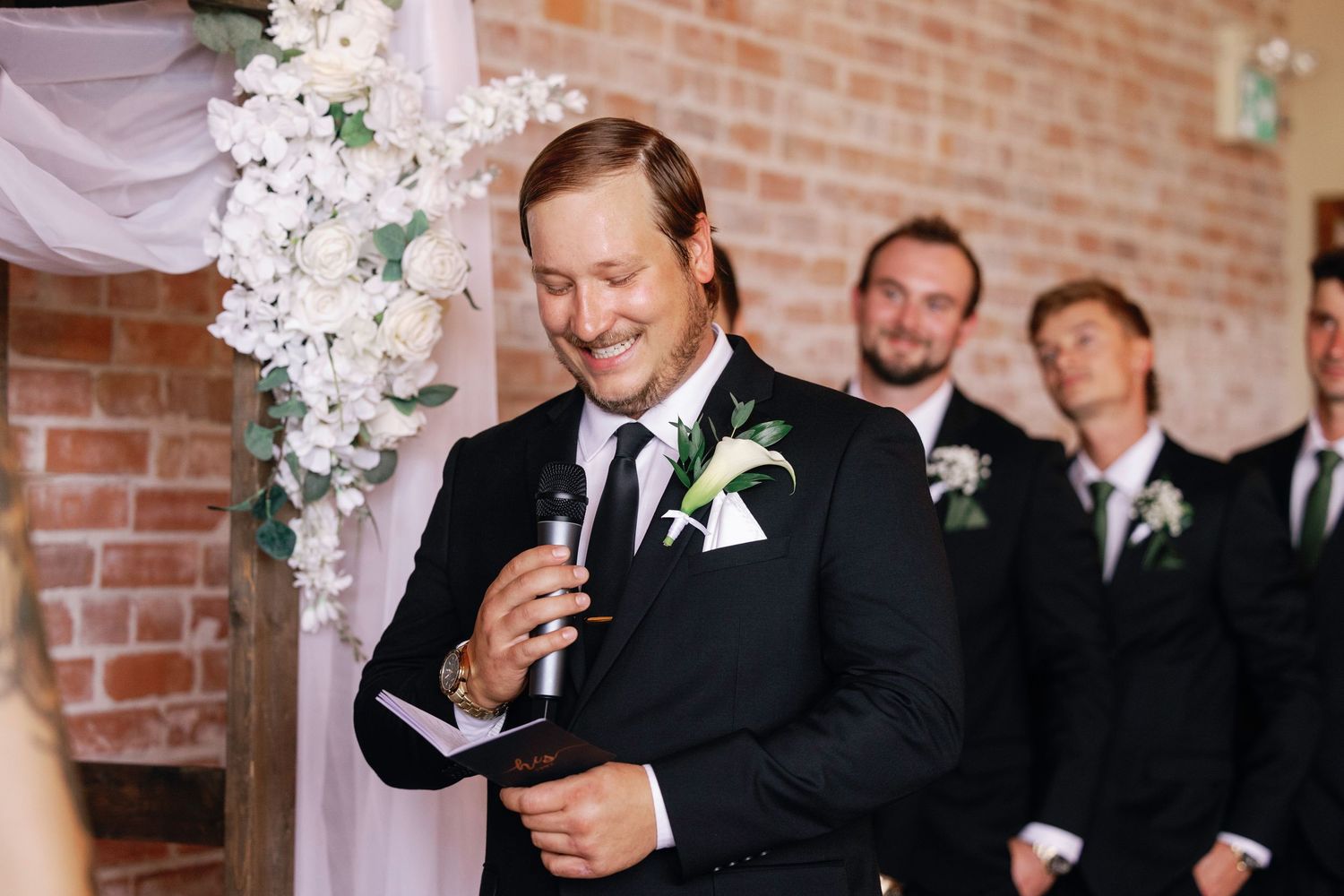 Wedding celebration in a rustic brick venue with exposed wooden beams and white floral decorations.