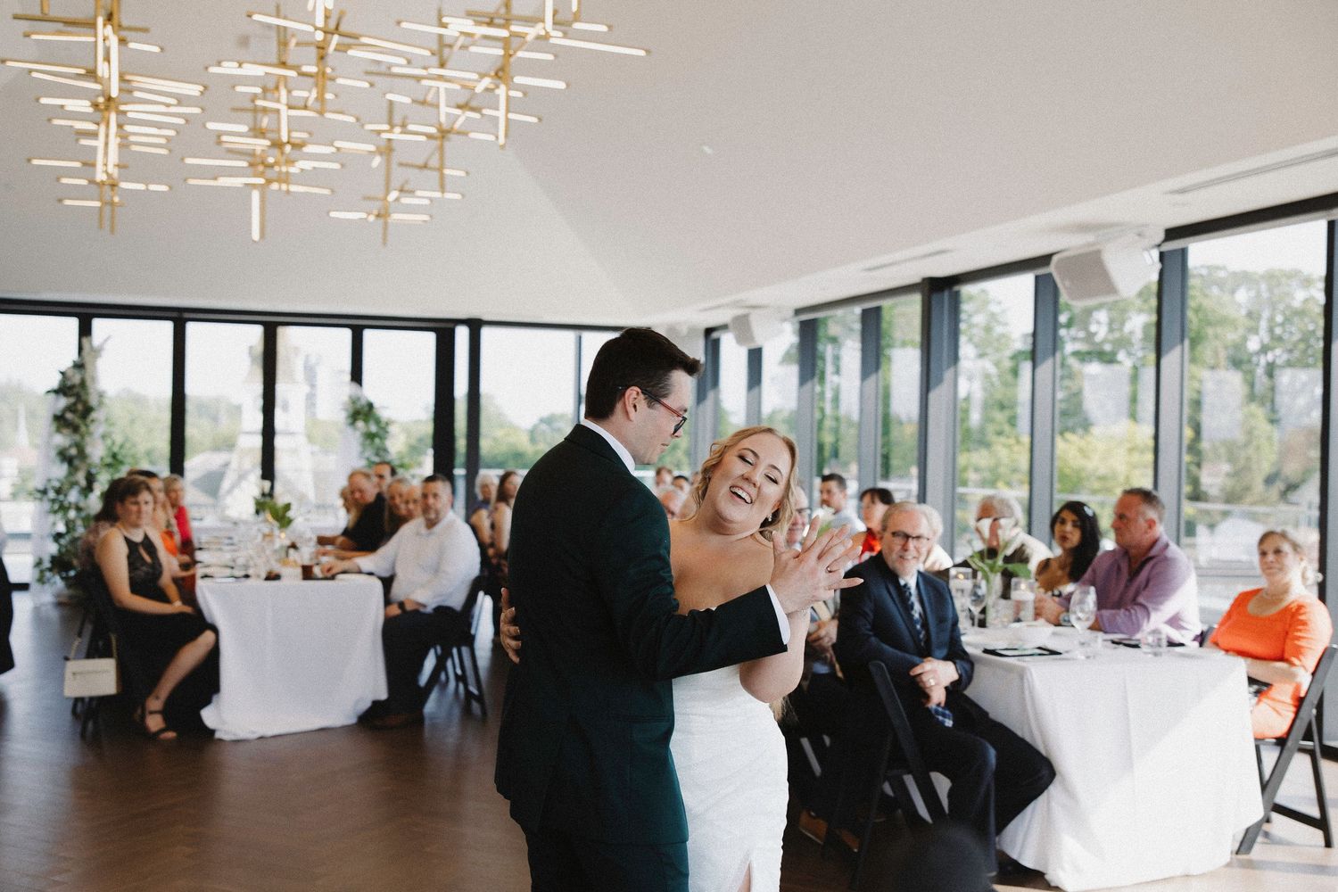 Modern reception venue with floor-to-ceiling windows and elegant lighting fixtures.