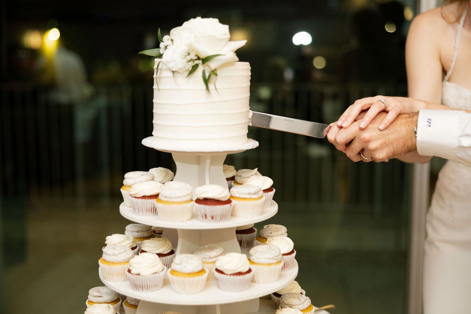 A tiered display of wedding desserts including macarons and cupcakes arranged on elegant white stands.