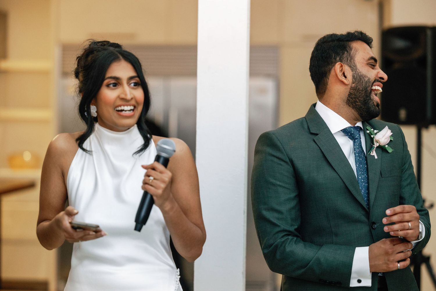 Couple delivering heartfelt wedding speeches with microphones at indoor venue.