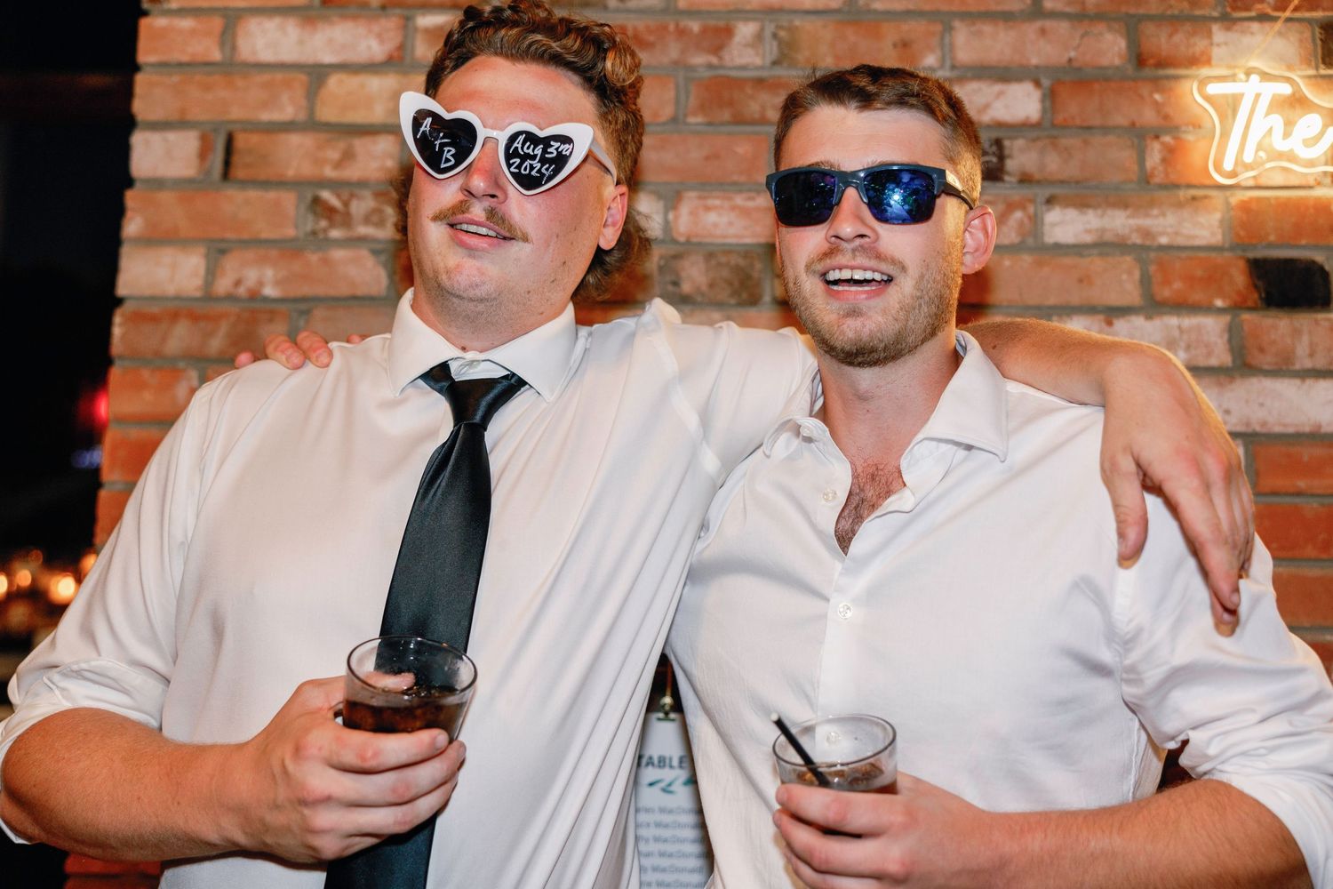 Group of guests wearing sunglasses and formal attire at an indoor celebration.
