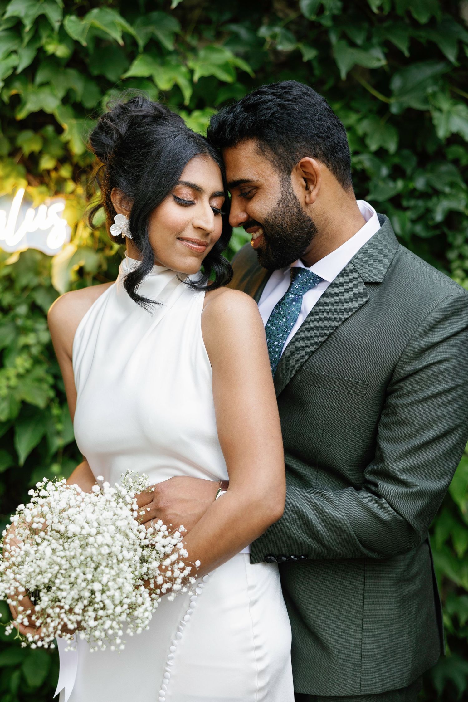 Romantic wedding portrait with baby's breath bouquet against green foliage.
