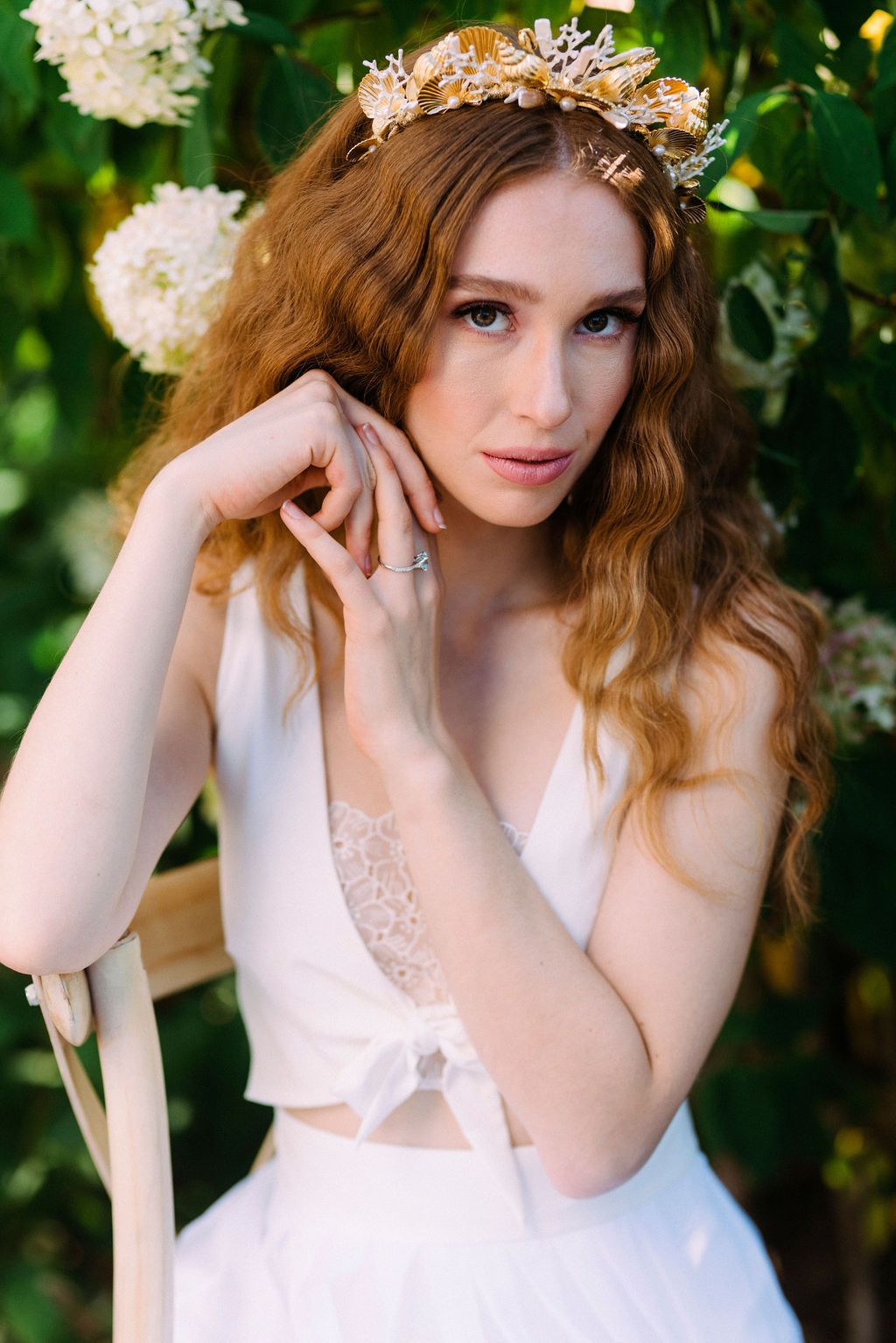 Romantic bridal portrait in a garden setting with white hydrangeas and golden crown headpiece.