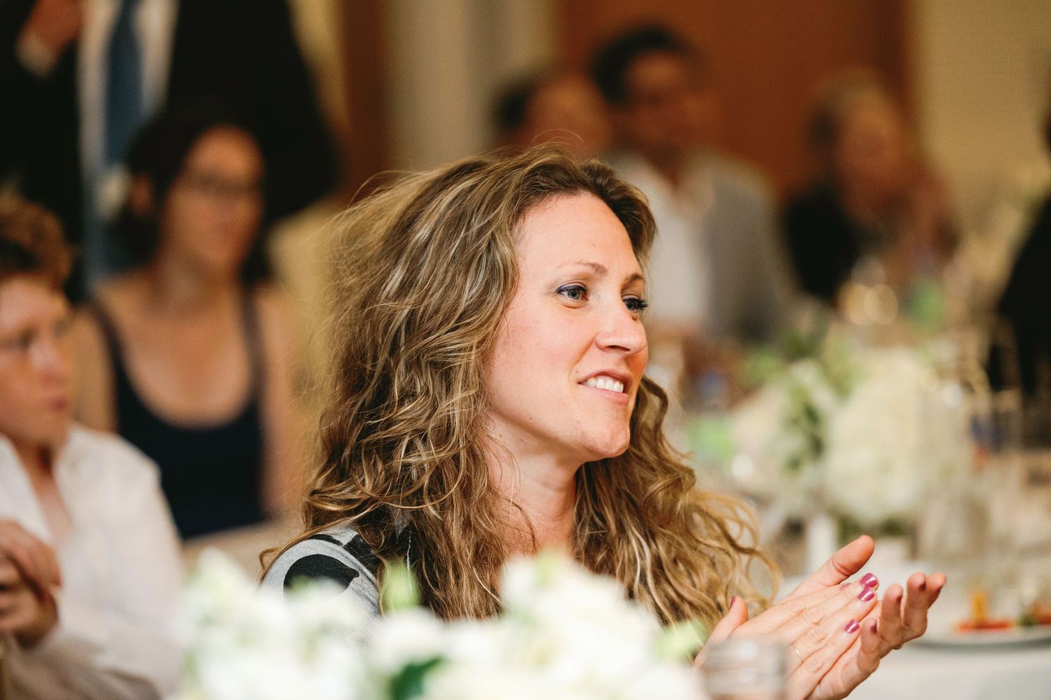 A person laughs joyfully at a formal dinner event while seated at an elegantly decorated table.