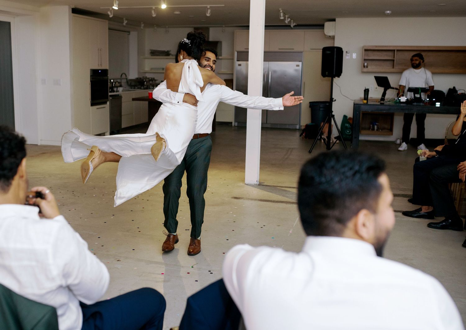 Playful wedding moment with bride being lifted in celebration at indoor reception.