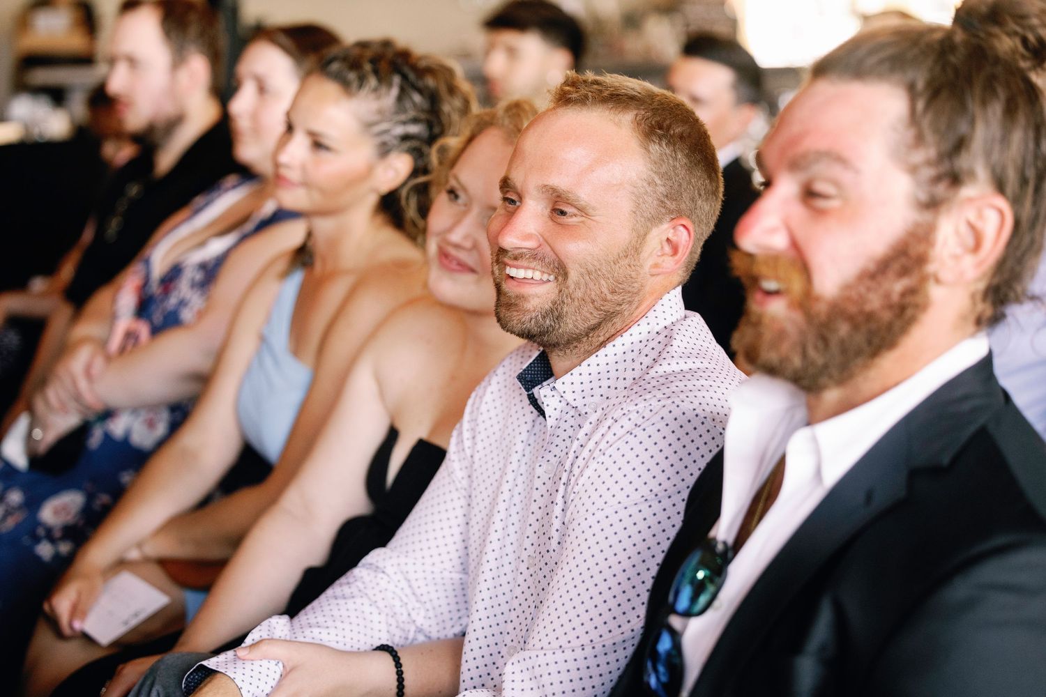 Wedding guests react with laughter and joy during an emotional ceremony moment.