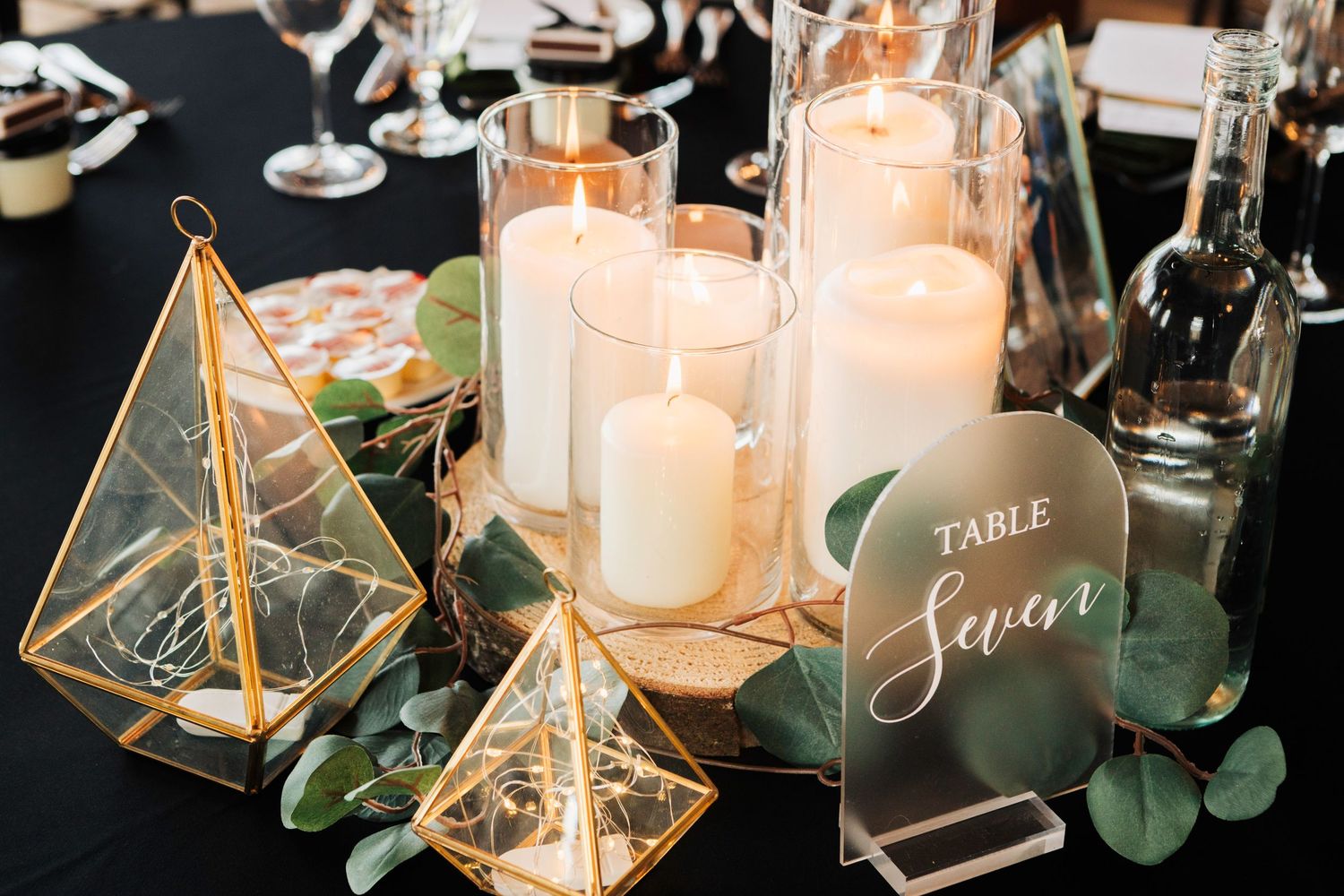 Elegant wedding table decor featuring geometric terrariums, candles, and eucalyptus greenery with soft lighting.