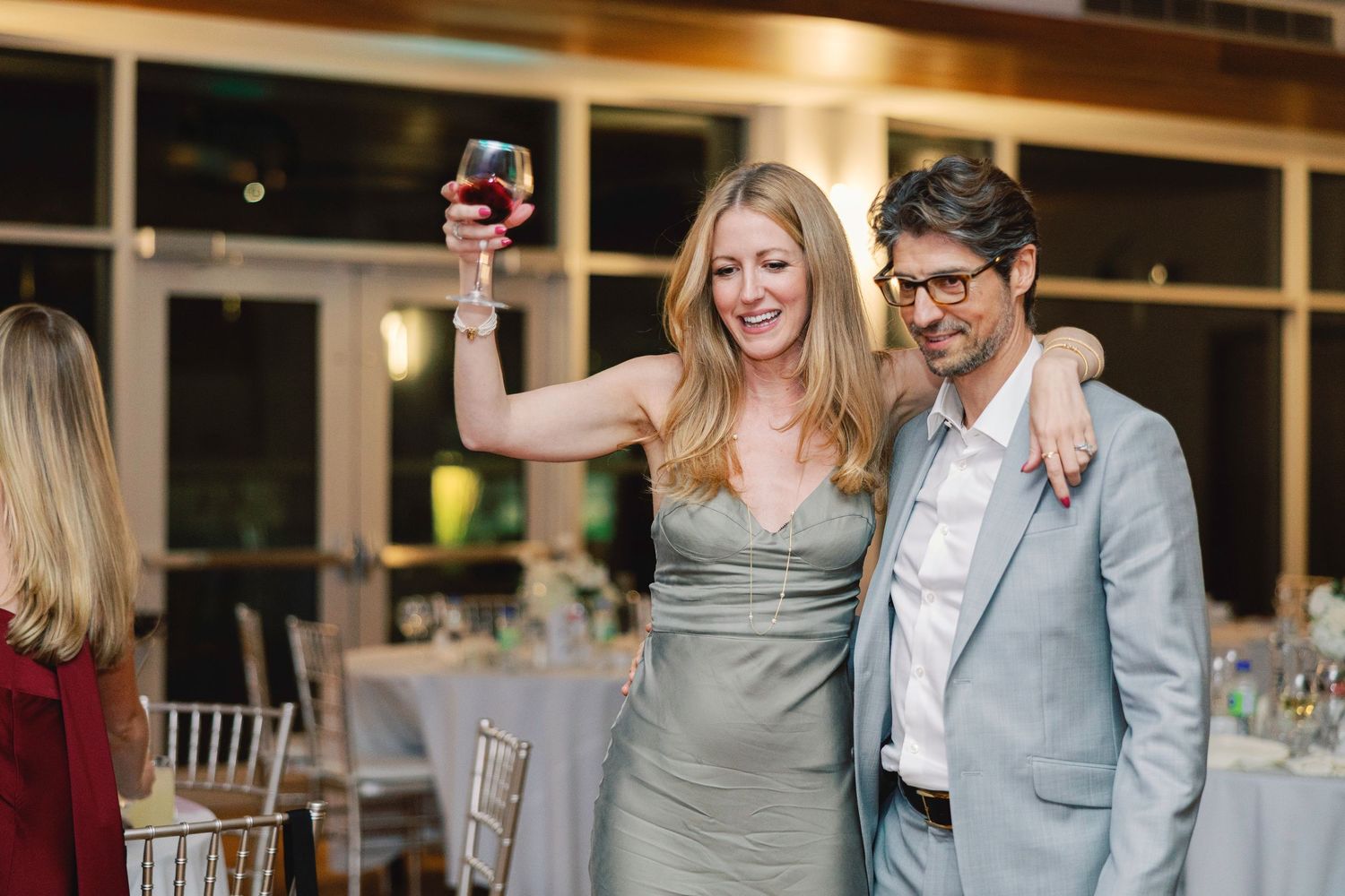 Couple laughing and dancing together during a wedding celebration in an elegant indoor venue.
