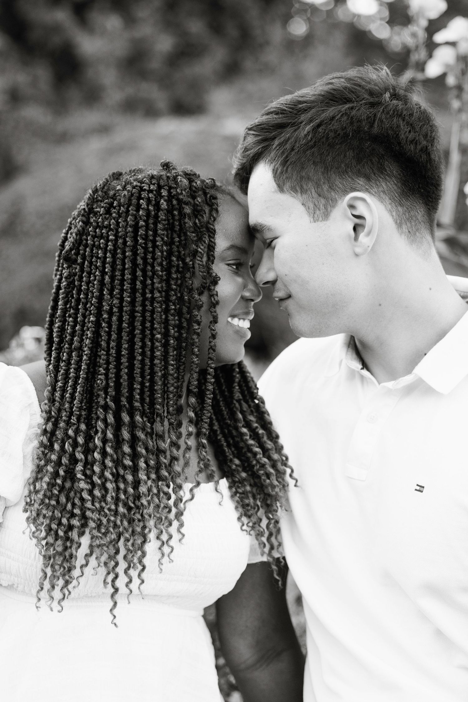 A romantic black and white portrait of a couple sharing an intimate moment outdoors.