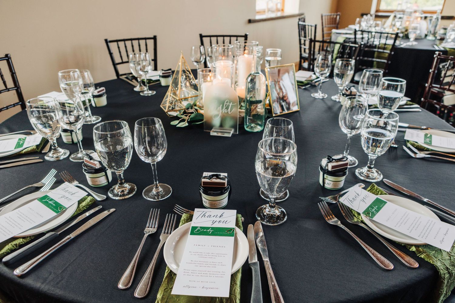 Elegant table settings with wine glasses and place cards at a formal dinner reception.