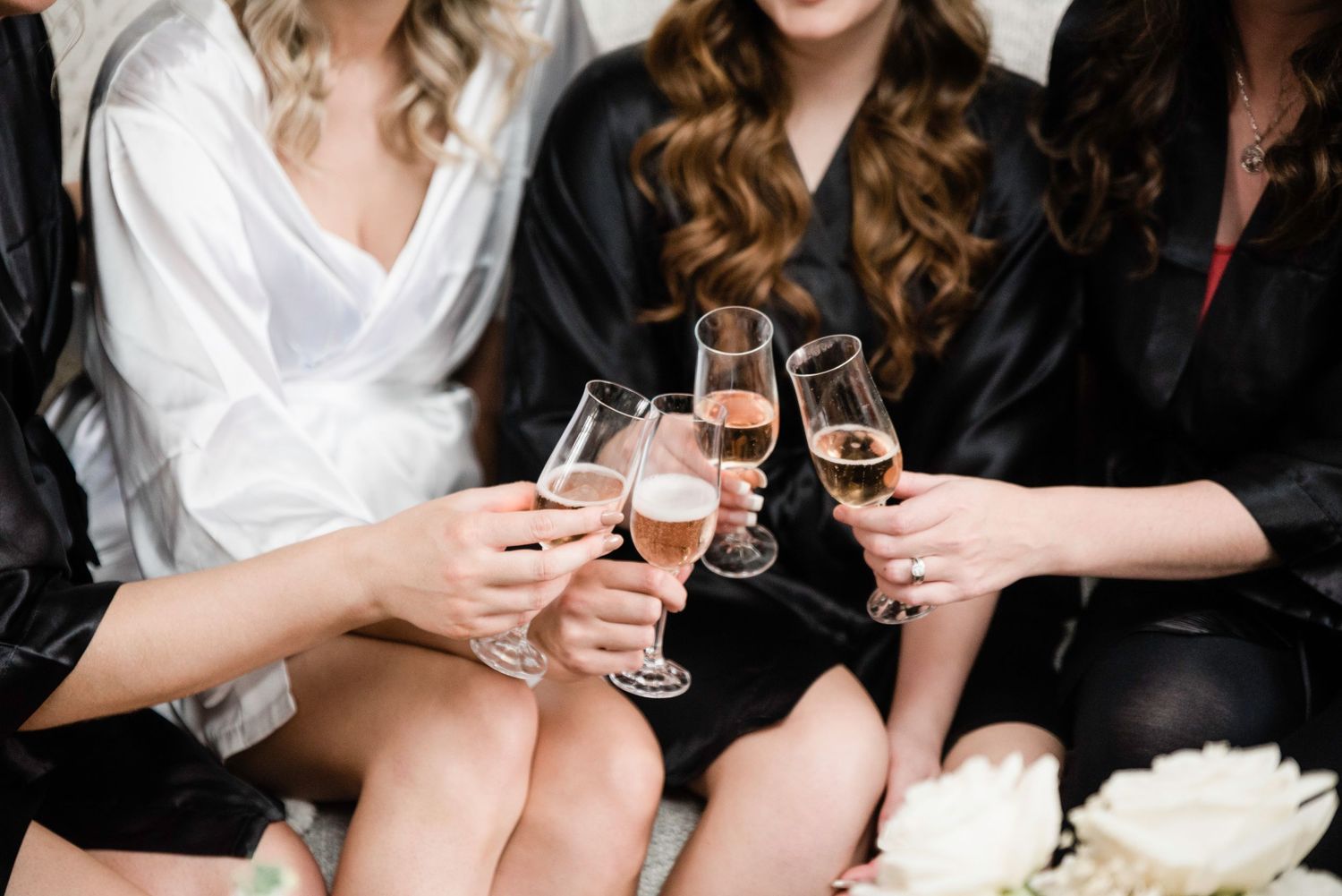 Celebration toast with champagne glasses among friends in matching robes.