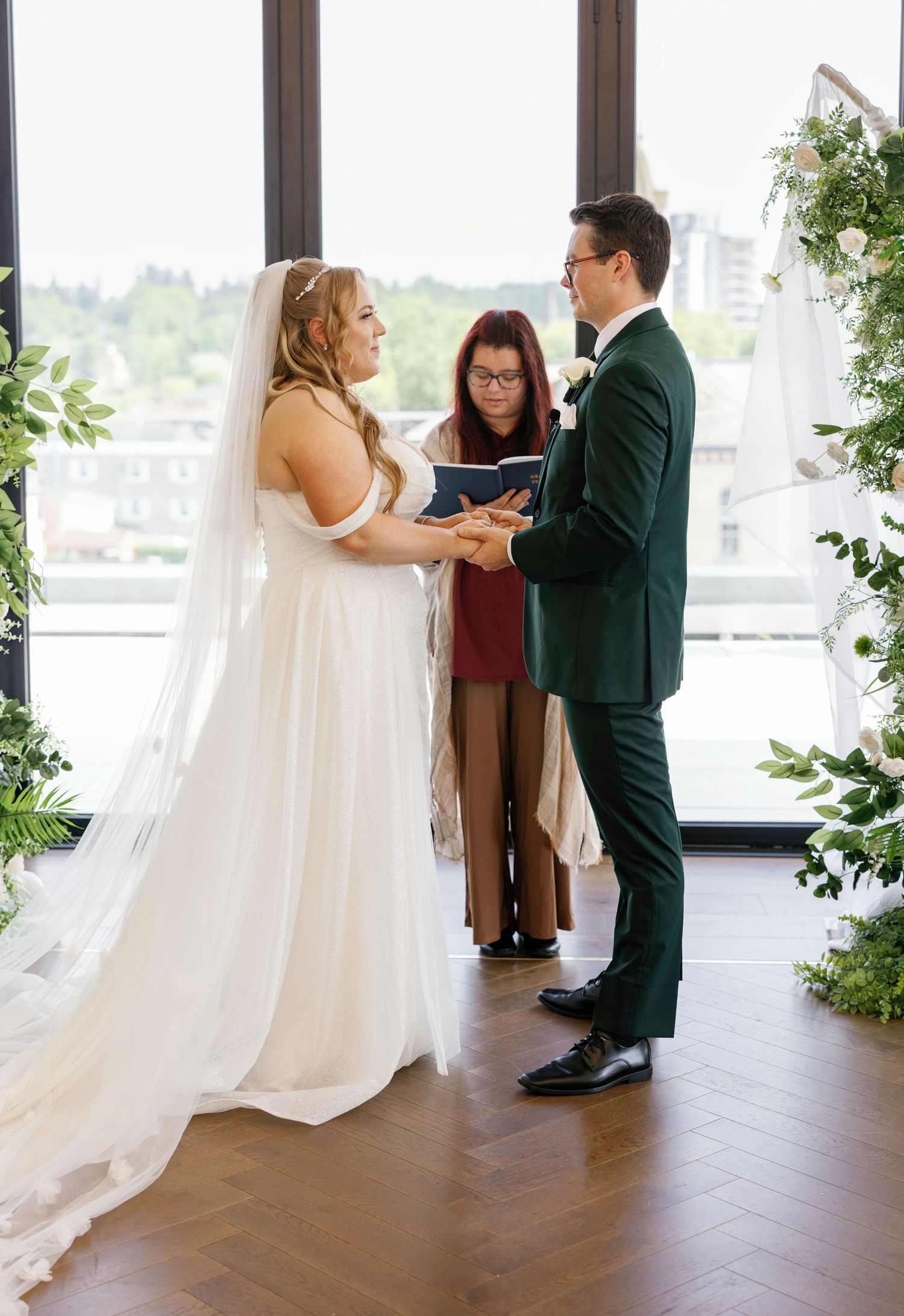 First look sequence showing couple sharing an intimate moment in a bright indoor venue with large windows and greenery.