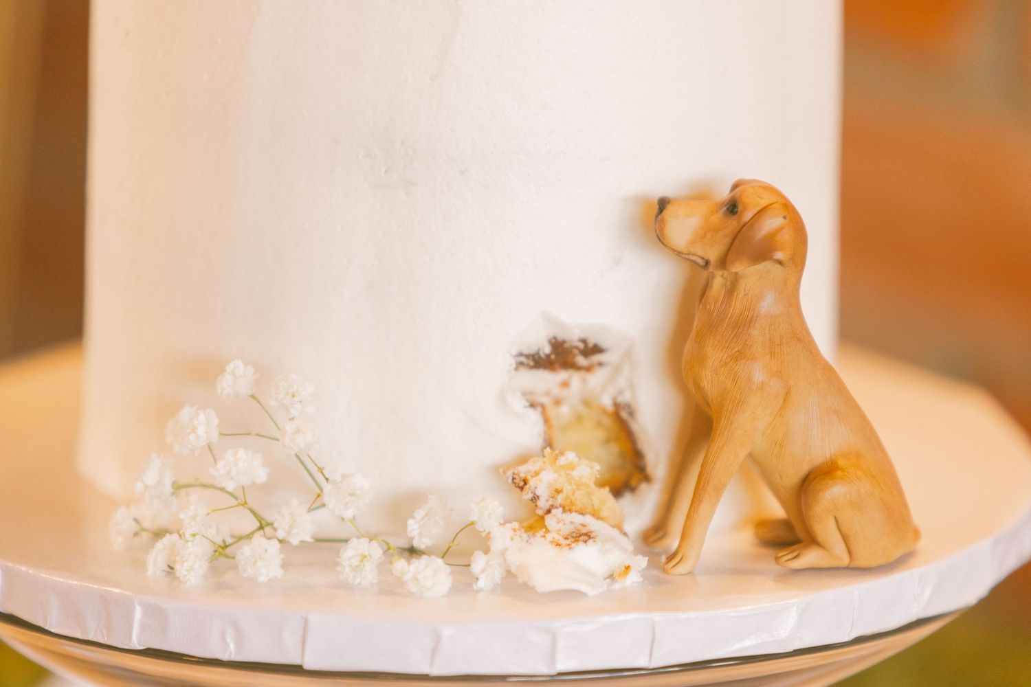 A rustic wedding cake decorated with small golden animal figurines sits on display at a reception.