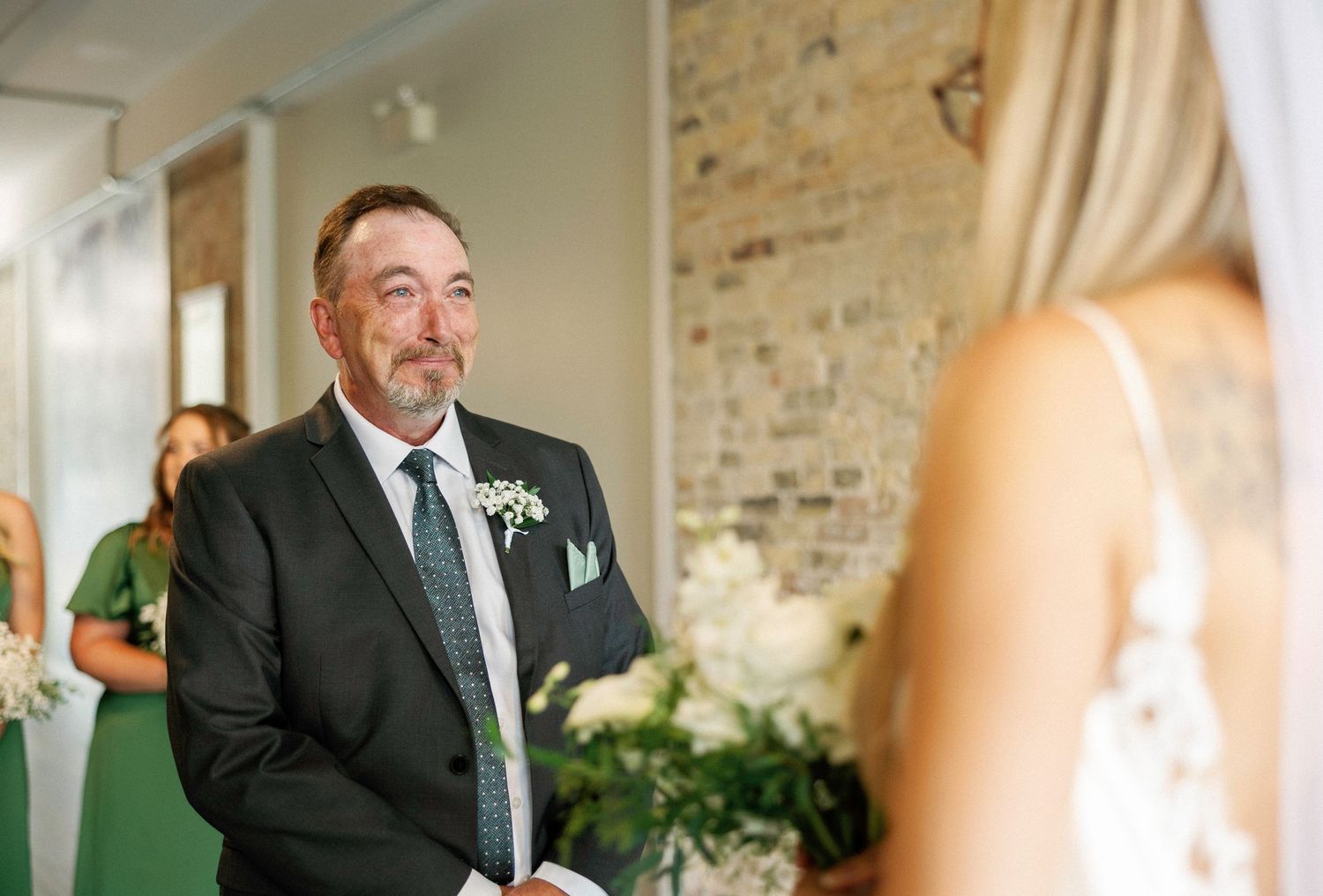 Candid emotional reactions captured during a wedding ceremony in a bright venue with exposed brick walls.