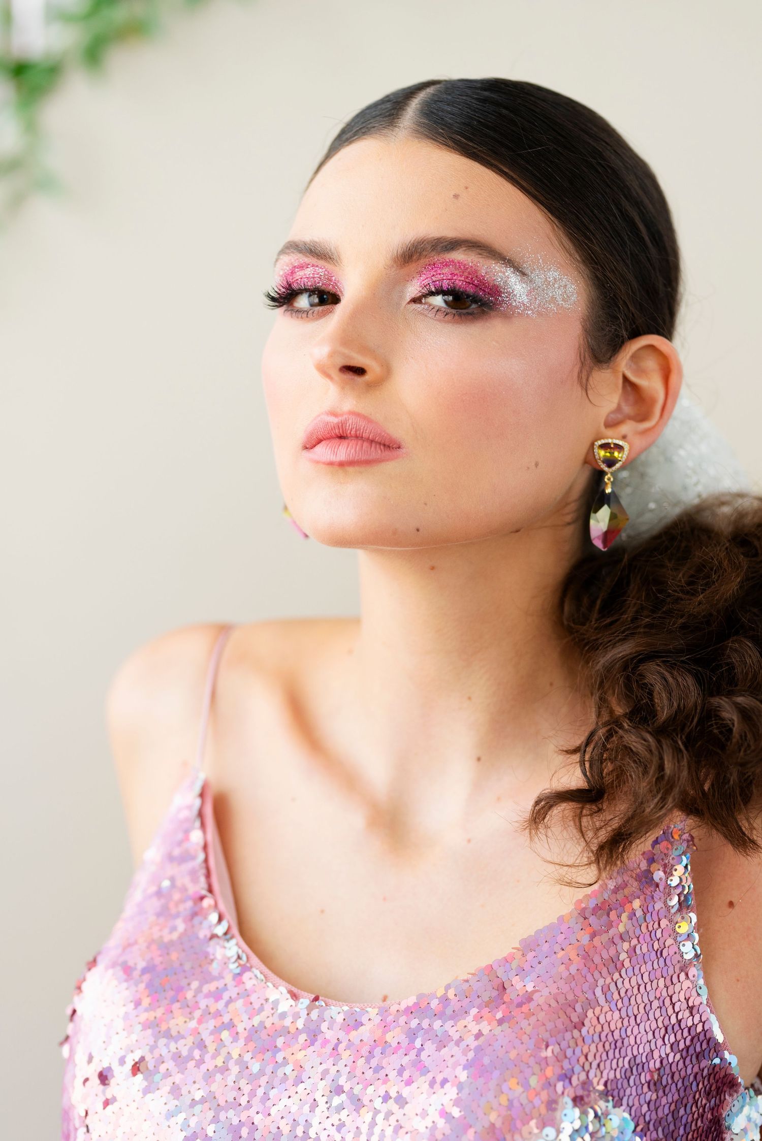 Fashion portrait showcasing sparkly pink eye makeup and sequined top with glamorous styling.