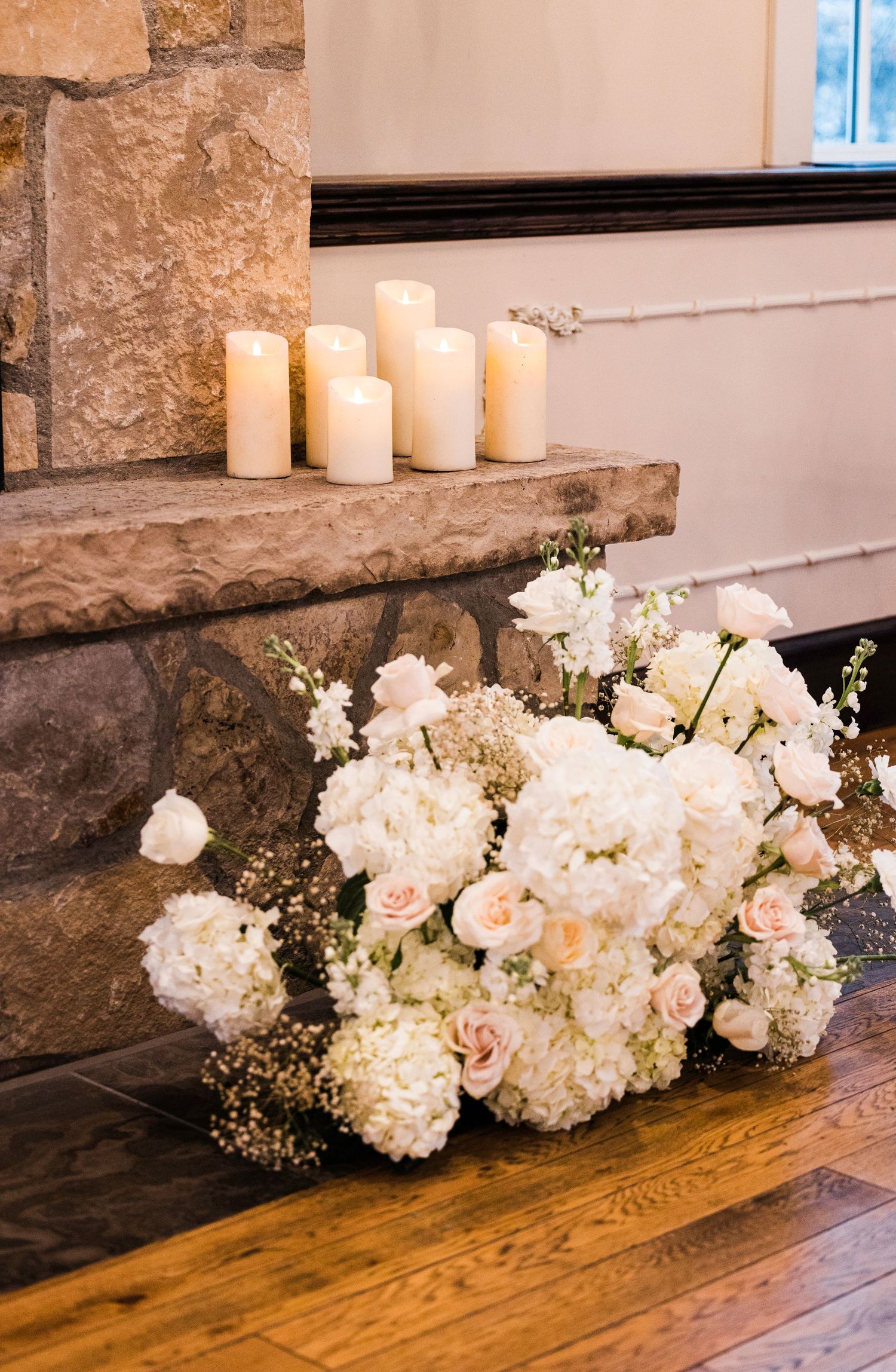 Romantic white floral arrangements with candles displayed on wooden surface.
