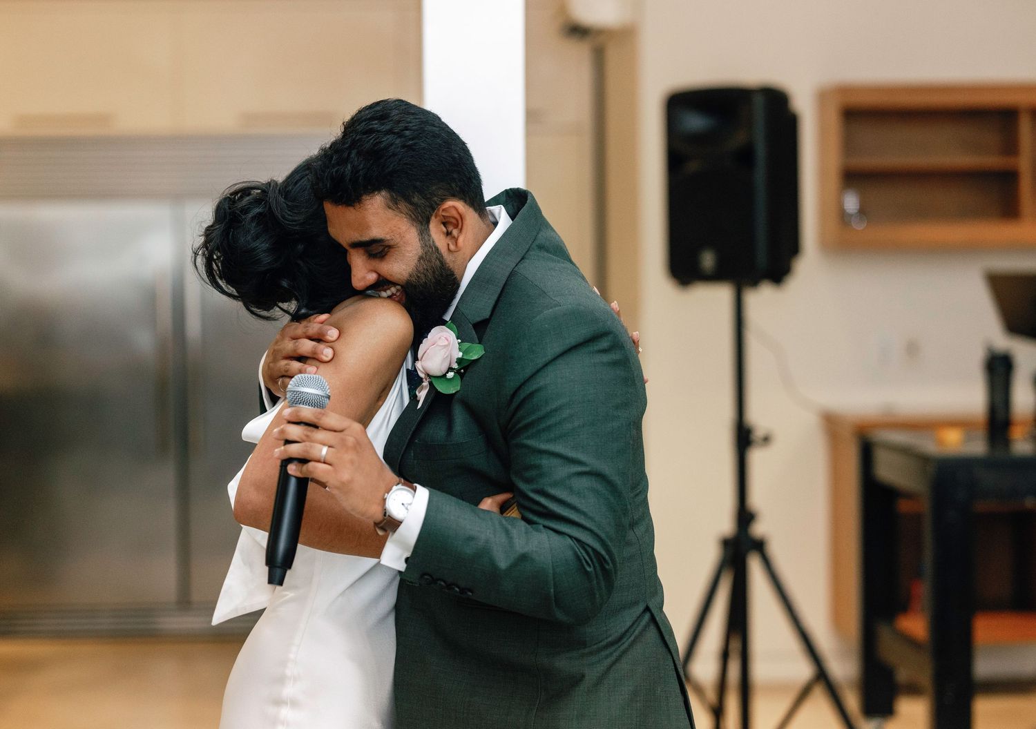 Emotional wedding moment as couple embraces during reception speeches.