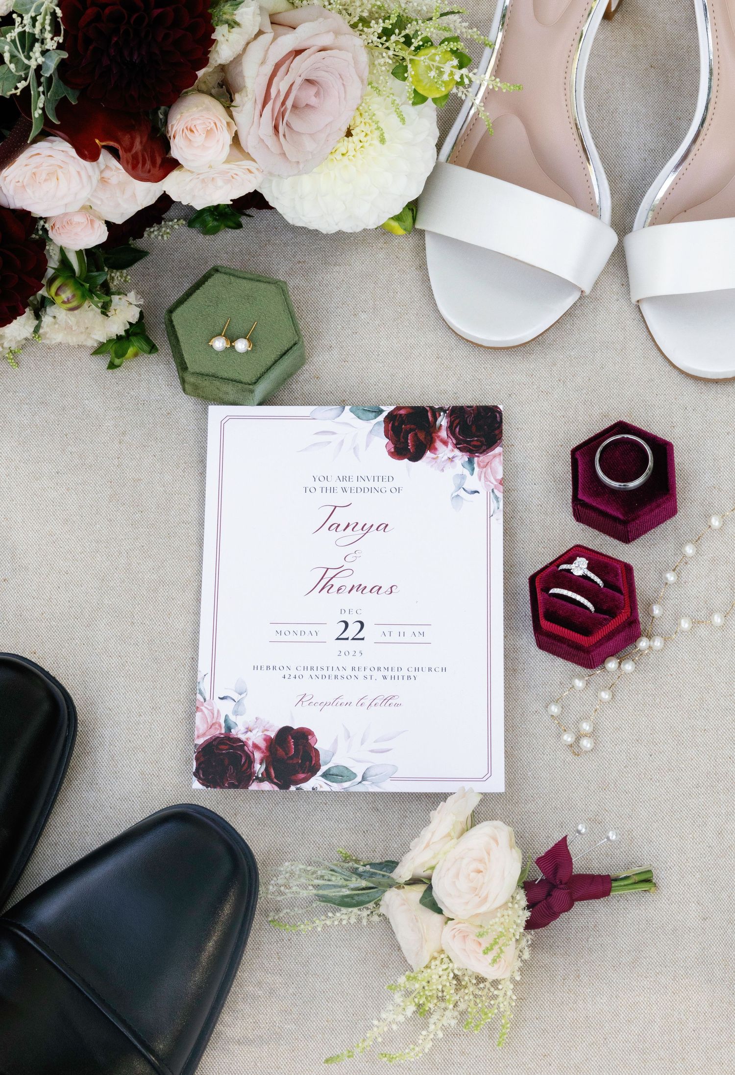 Wedding details flatlay with invitation, rings, shoes and pink roses on grey background.