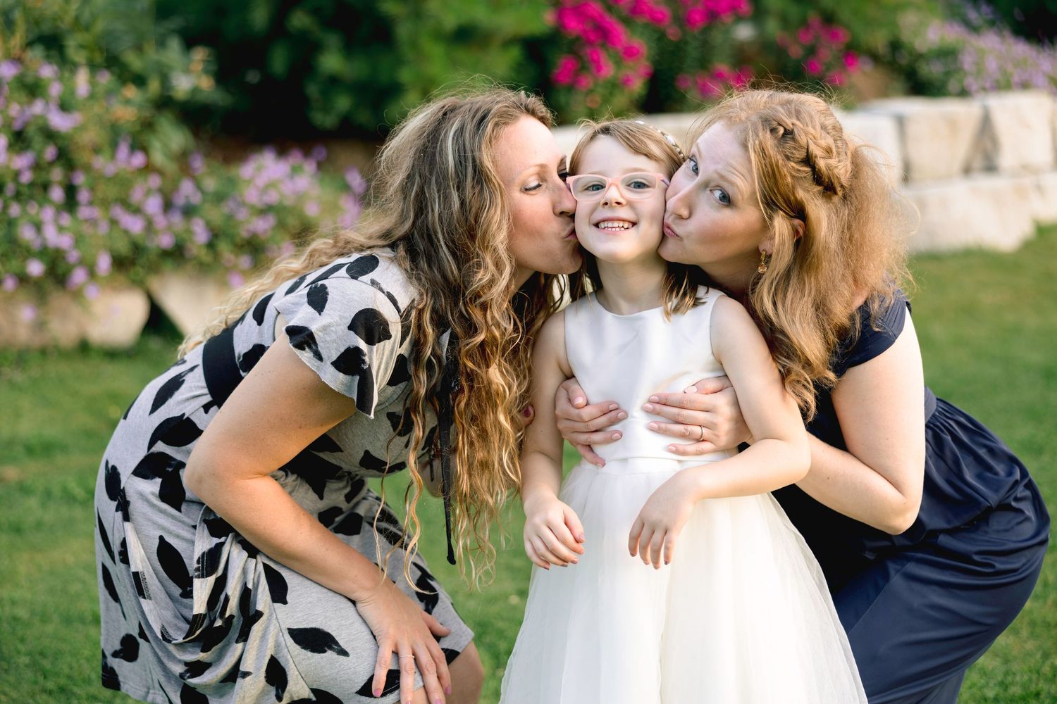 A loving family moment captured in a garden setting with blooming pink flowers and natural greenery.