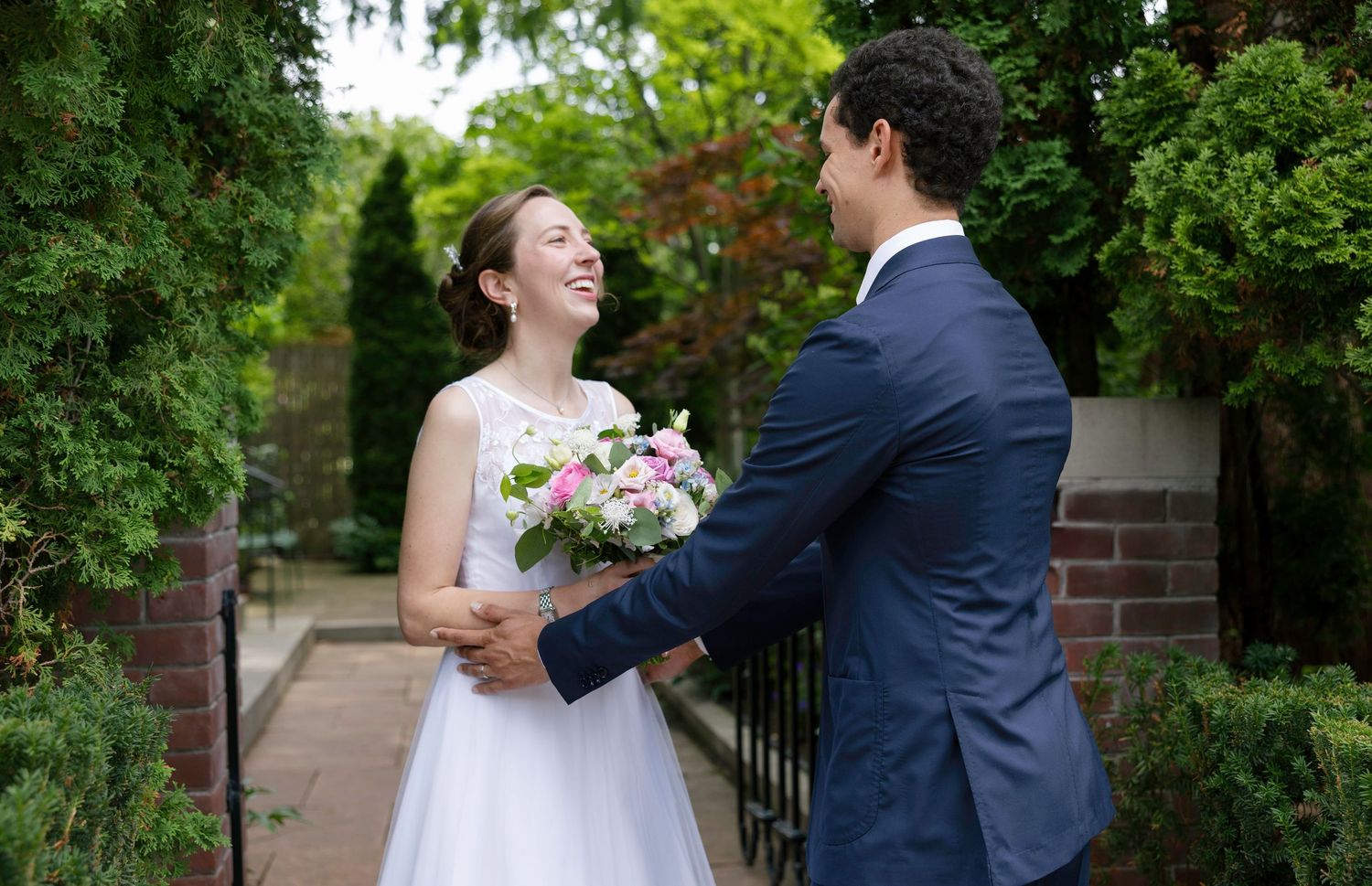 Candid wedding photos of couple sharing laughs on brick-lined garden path.
