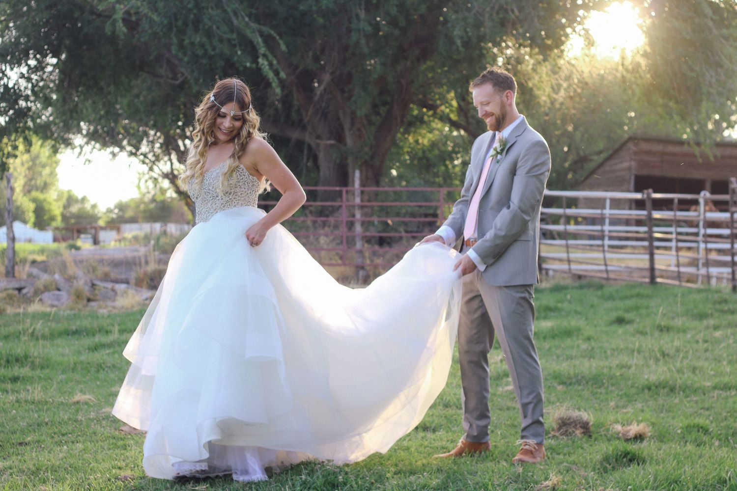 Wedding couple in a rustic outdoor setting with flowing white dress and grey suit.