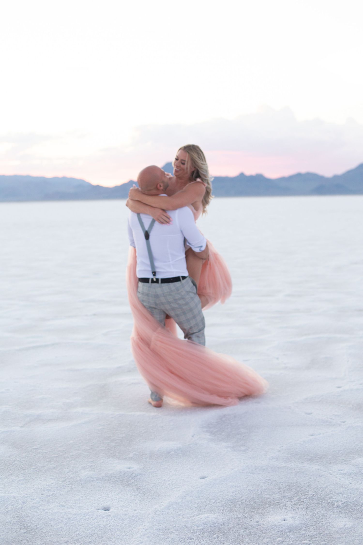 Intimate dance moment on salt flats with pink dress flowing in evening light.