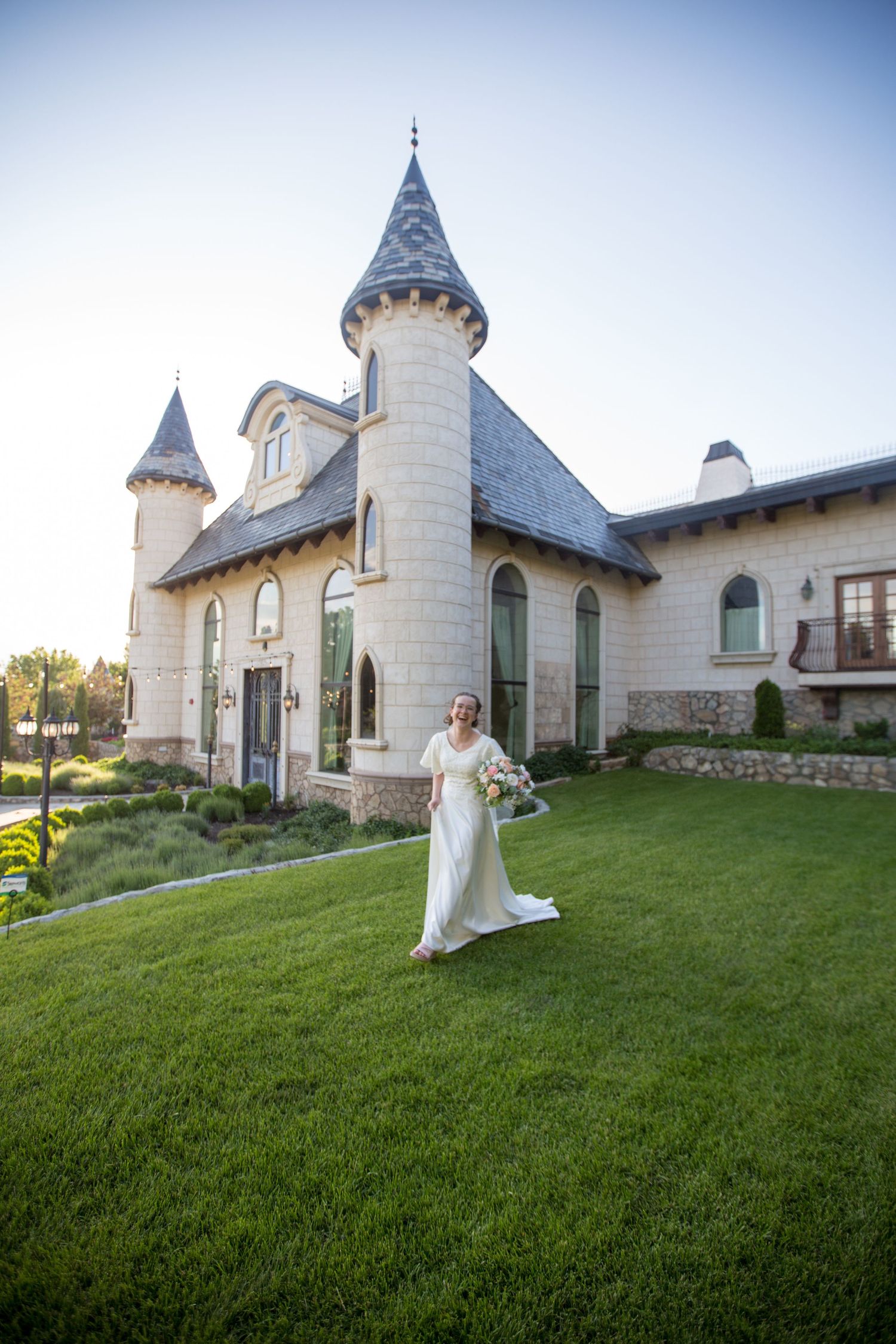 Fairytale wedding venue with stone turrets and arched windows frames outdoor bridal portrait.