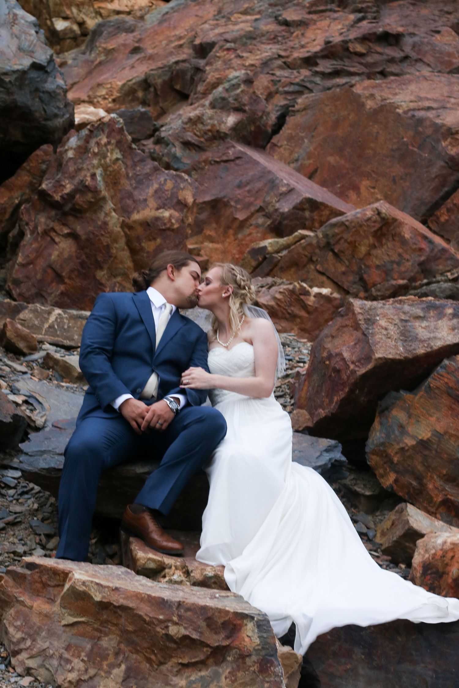 A romantic wedding photo shoot against red rock formations showing tender moments between newlyweds.