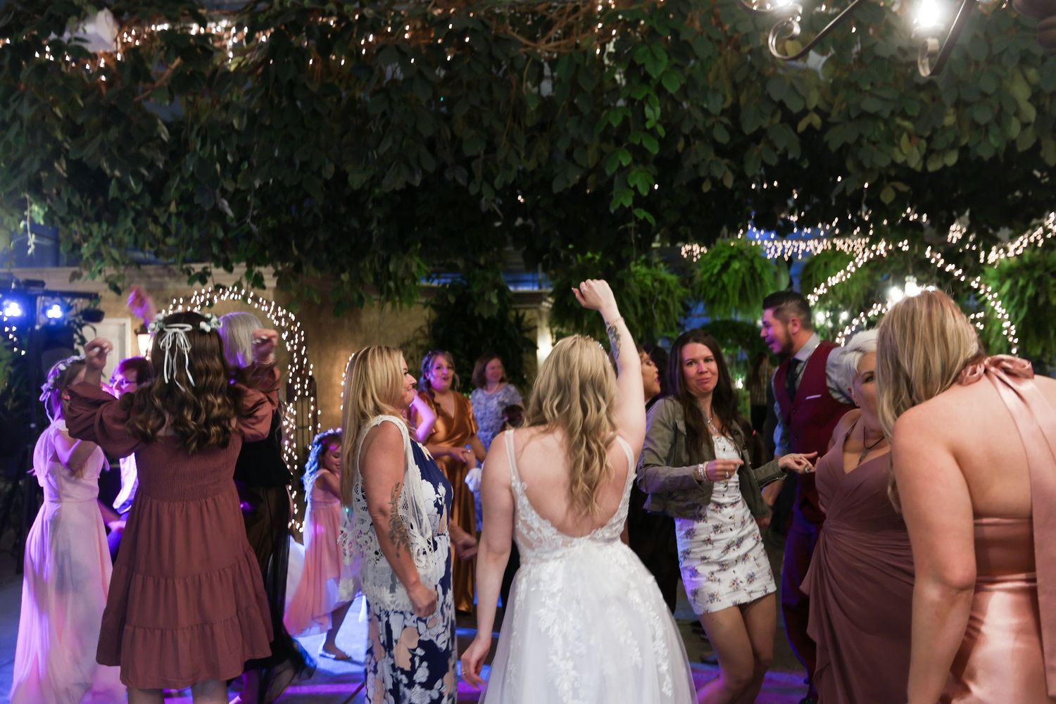 Wedding guests dance and celebrate on a dimly lit dance floor.