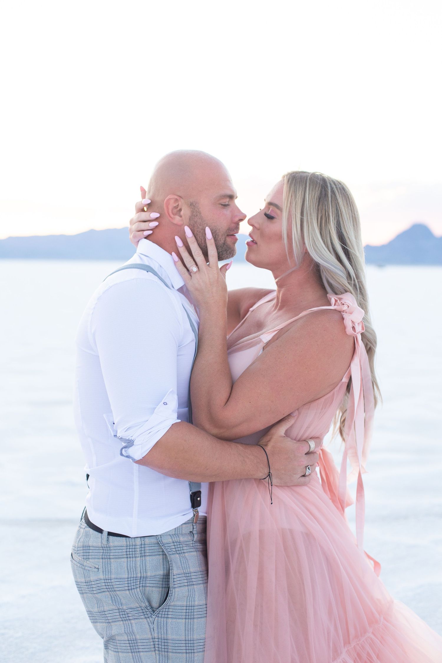 Intimate moment between couple in formal wear on scenic beach.