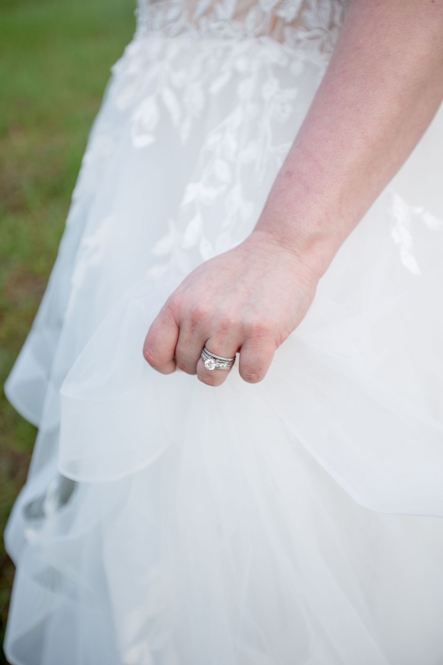 Close-up detail of delicate lace pattern on white wedding dress fabric.