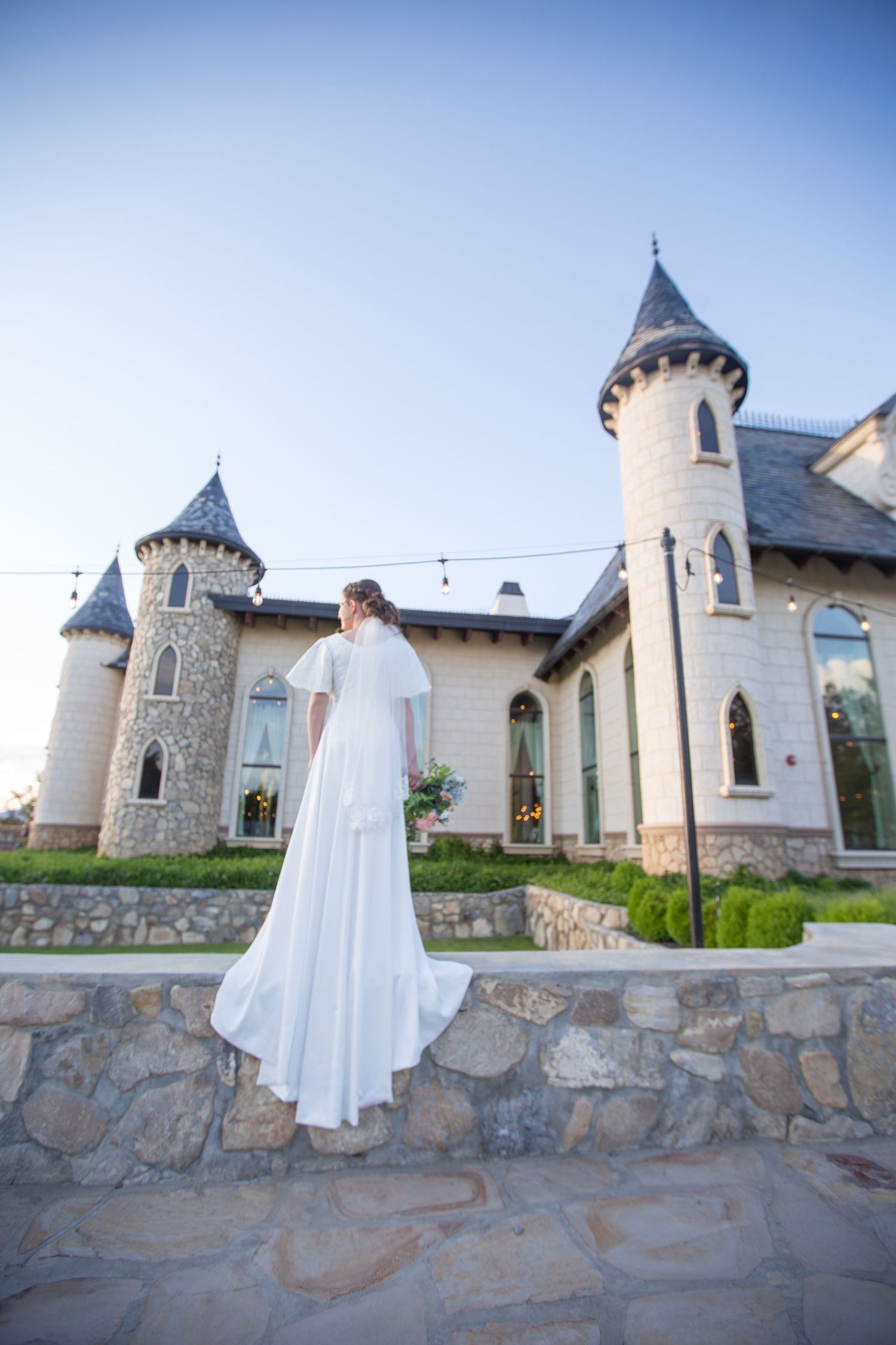 A flowing white dress captured at a castle venue with stone walls and spired towers.