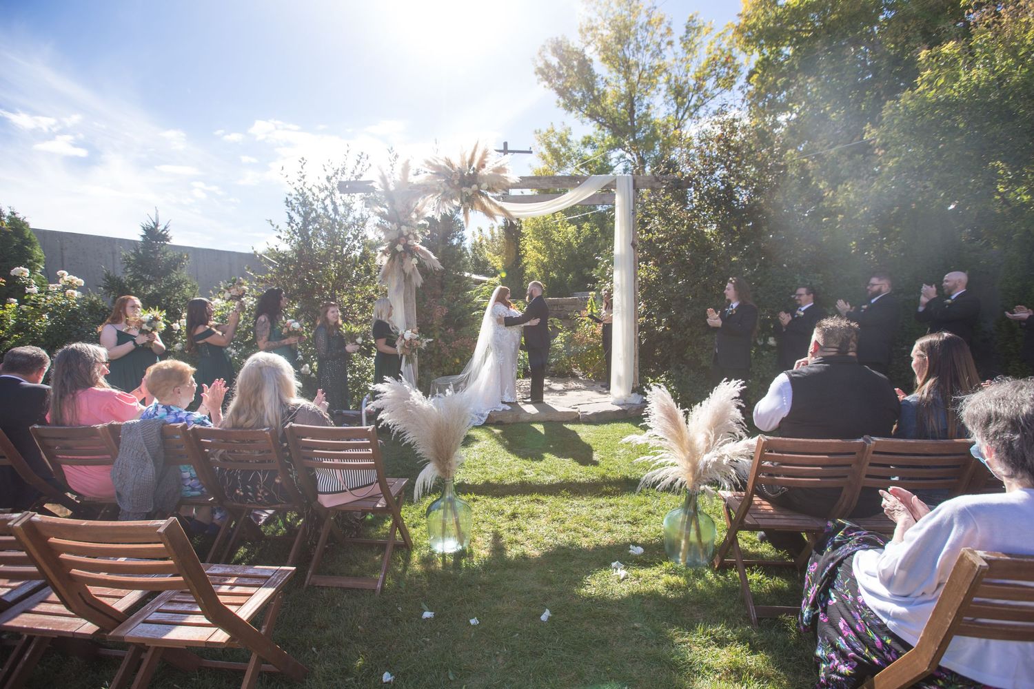 Outdoor wedding ceremony seating arrangement with natural sunlight filtering through trees.