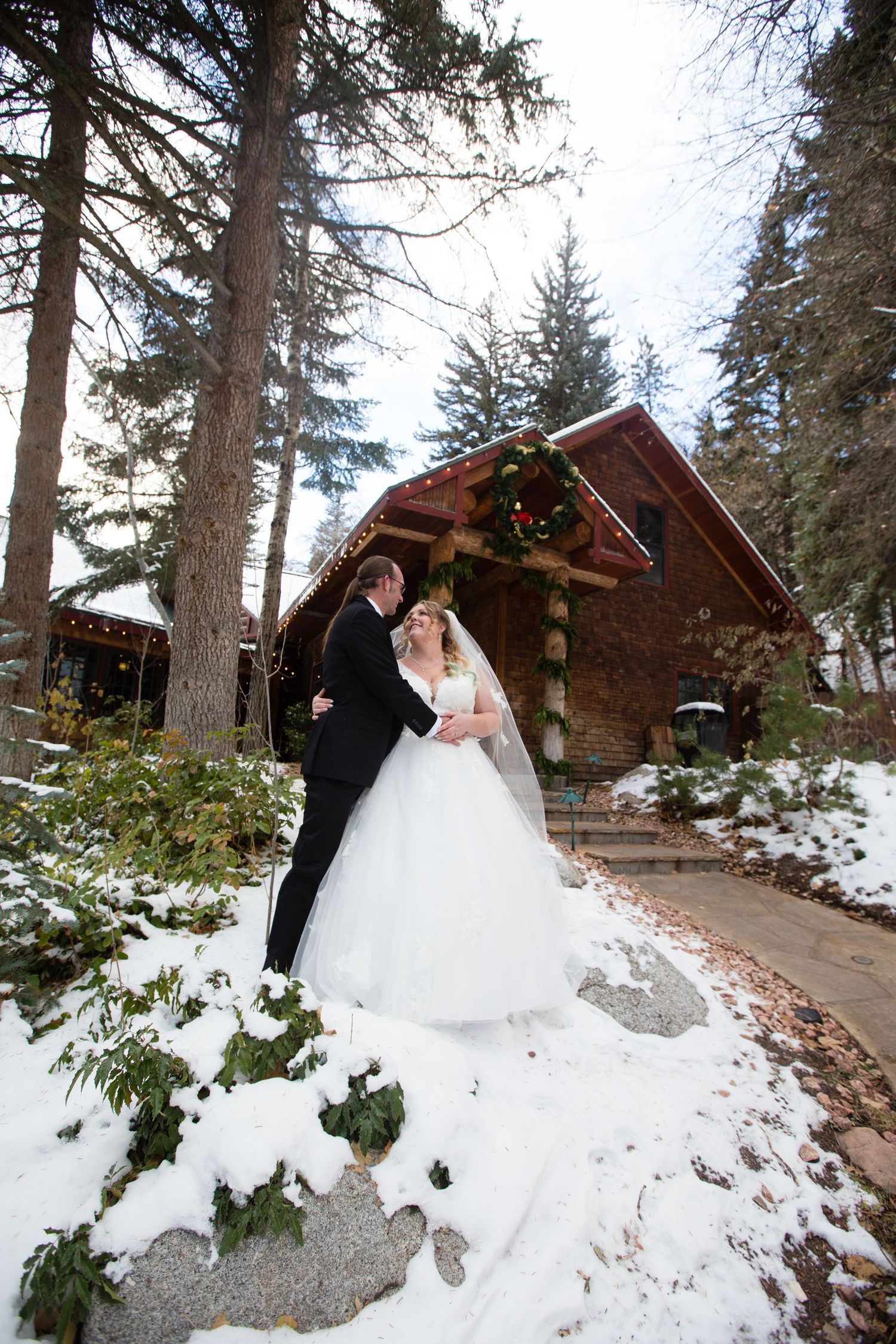 A winter wedding photoshoot featuring rustic cabins and snow-covered grounds in a mountain setting.