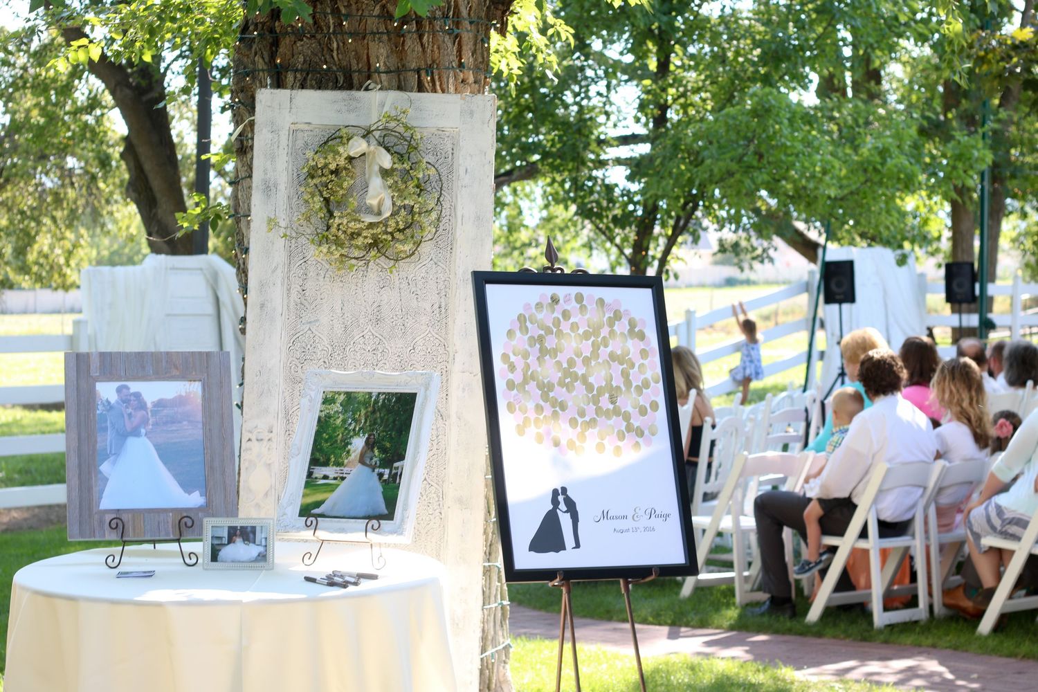 Rustic outdoor wedding decor with white frames and floral arrangements.