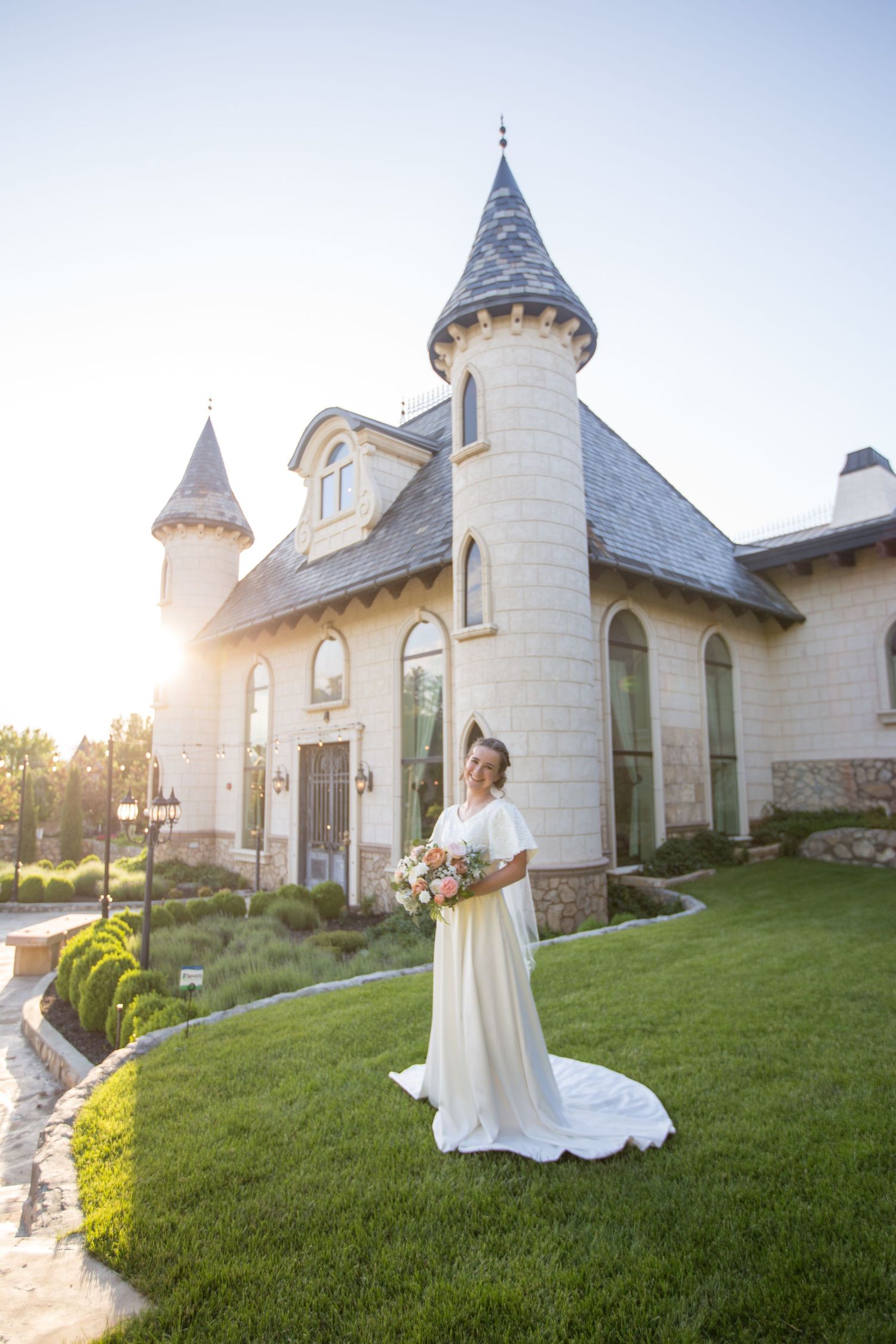 Sunlit wedding venue with dramatic spires and stone facade creates magical bridal setting.