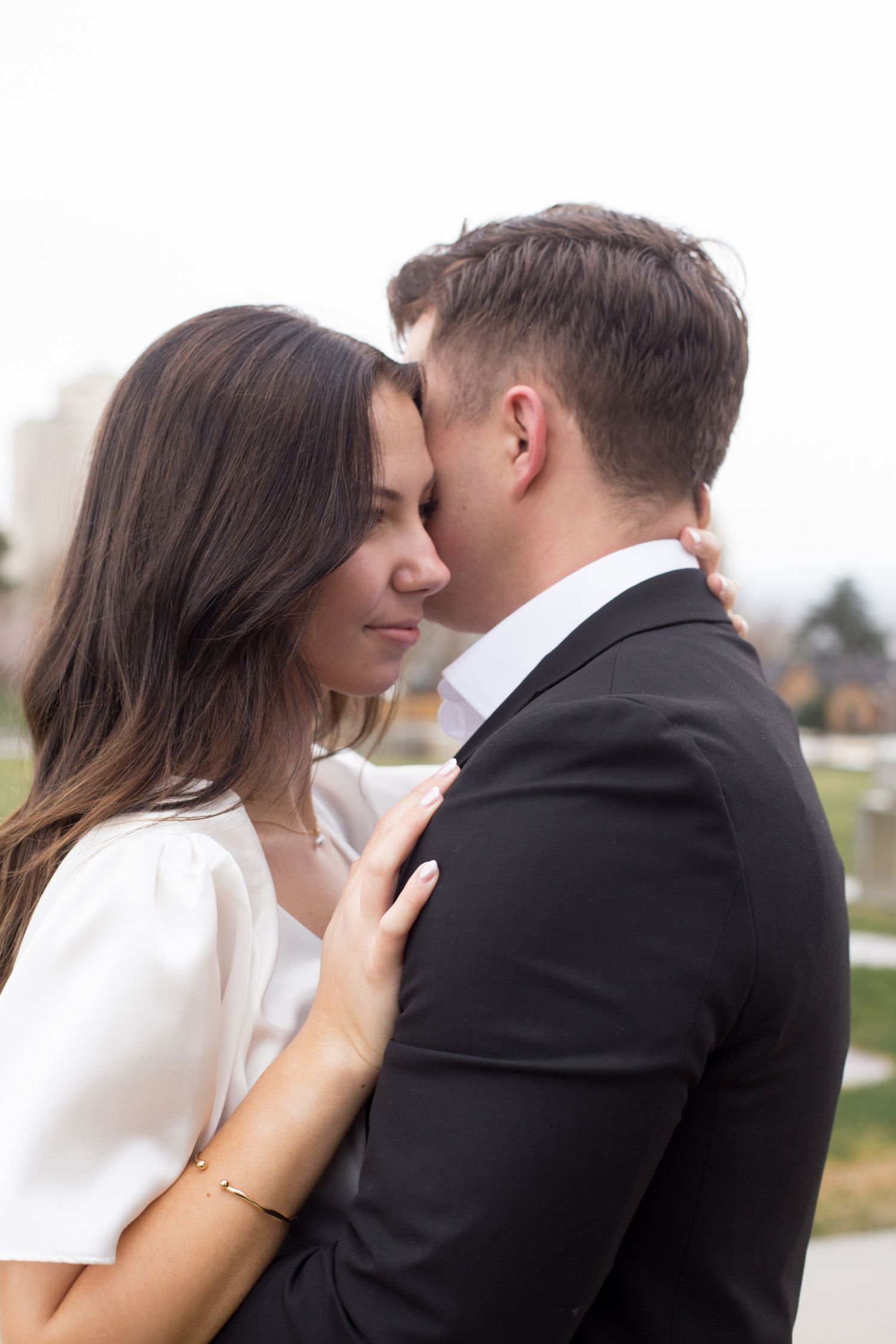 A romantic moment between a couple in formal attire against a soft background.