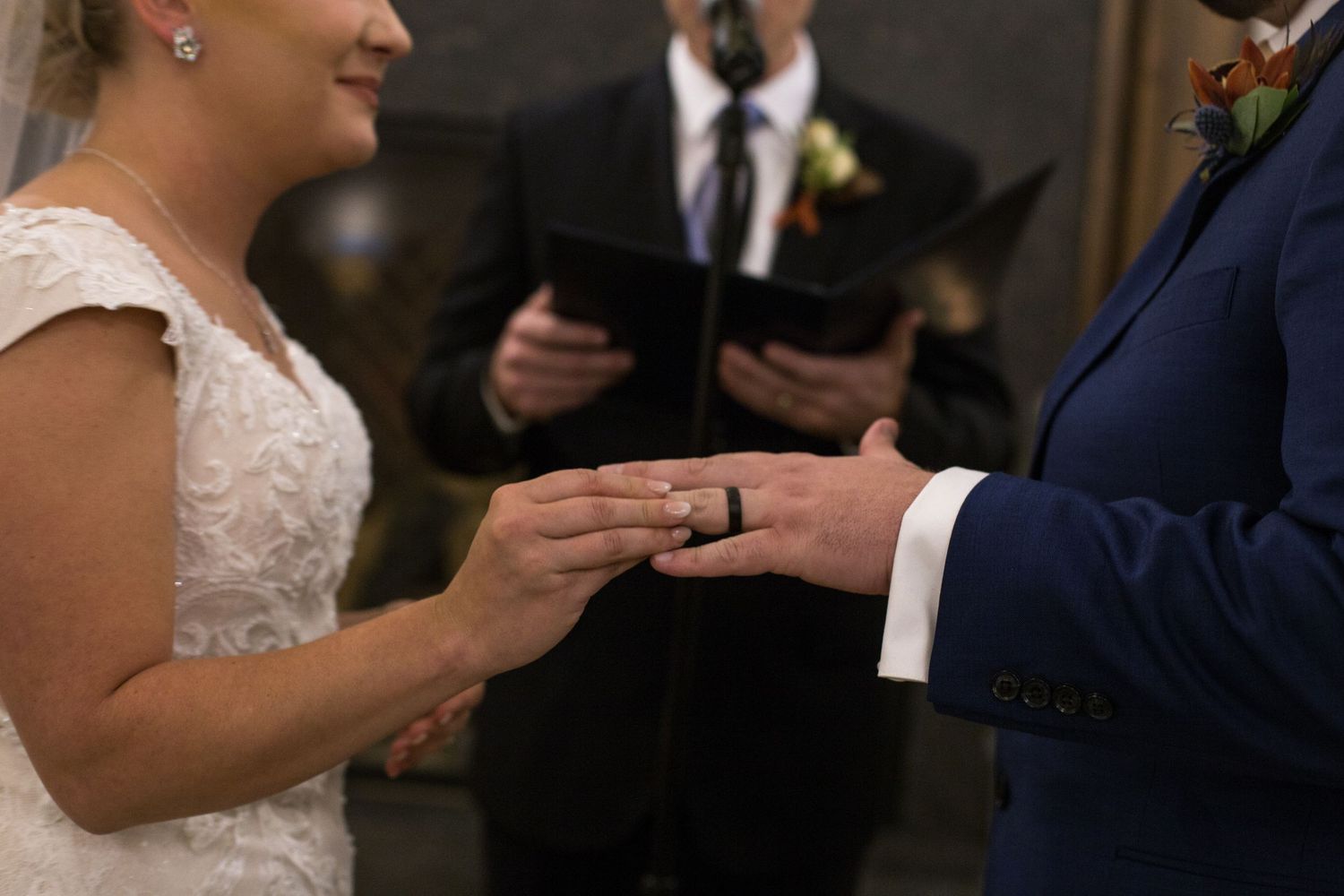 Close-up details of wedding rings being exchanged during a ceremony.