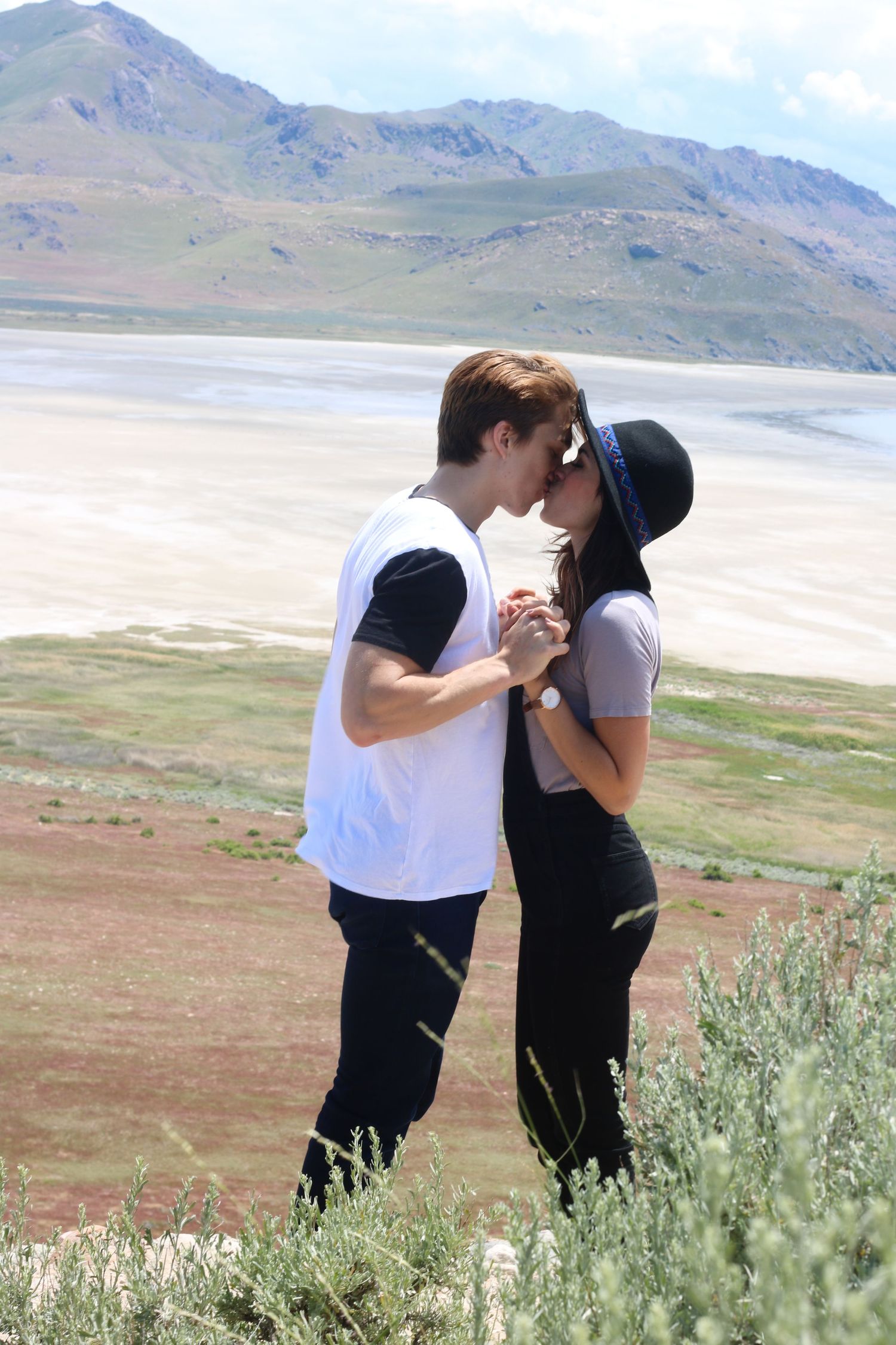 A couple shares an intimate moment against a backdrop of mountains and salt flats.