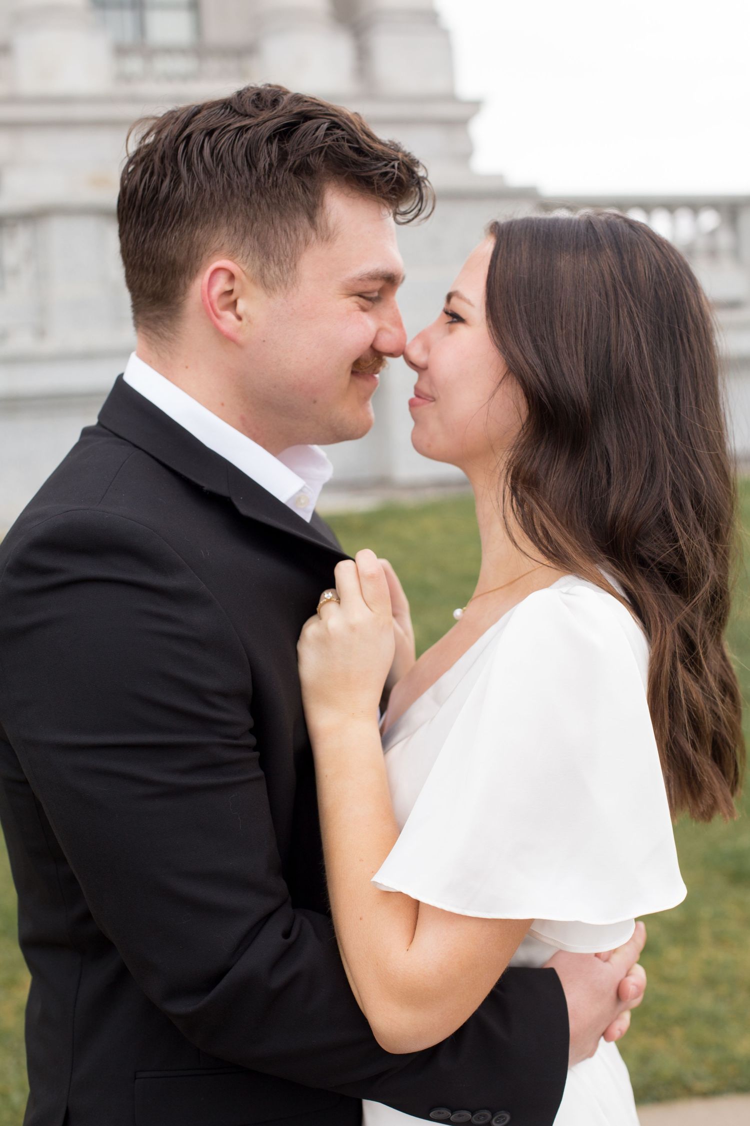 A romantic close-up moment between a couple in formal wedding attire.